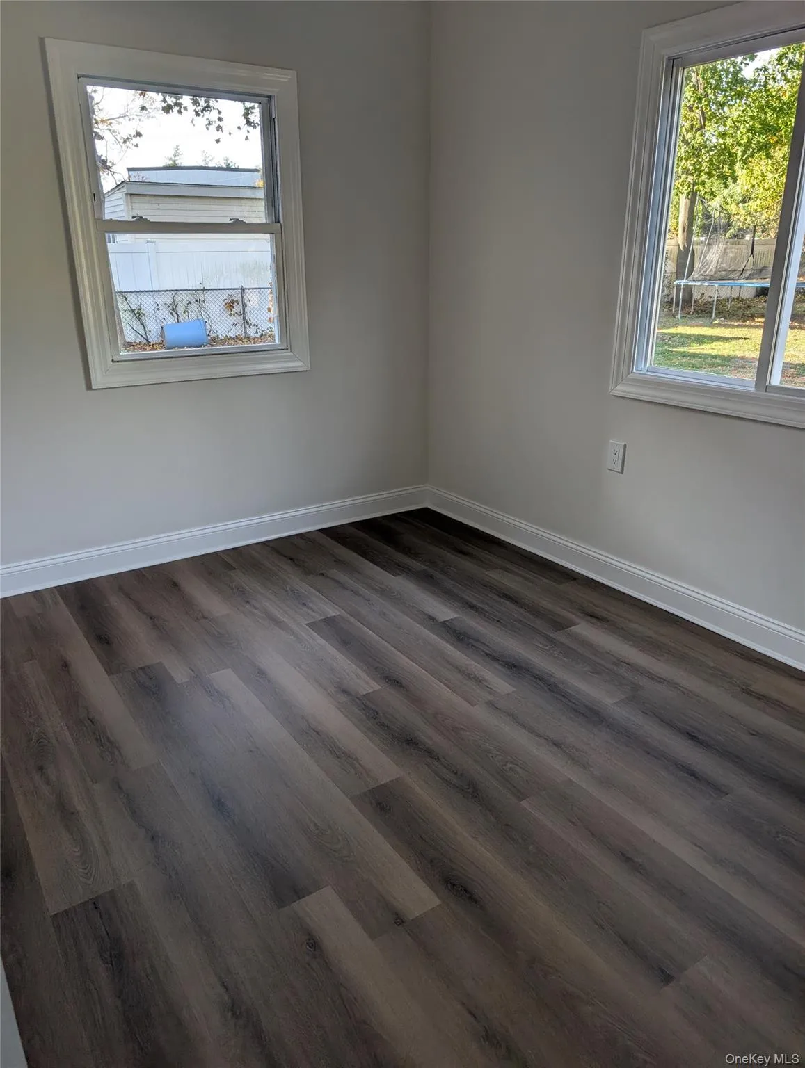 Empty room featuring baseboards and dark wood-style floors Empty room featuring baseboards and dark wood-style floors