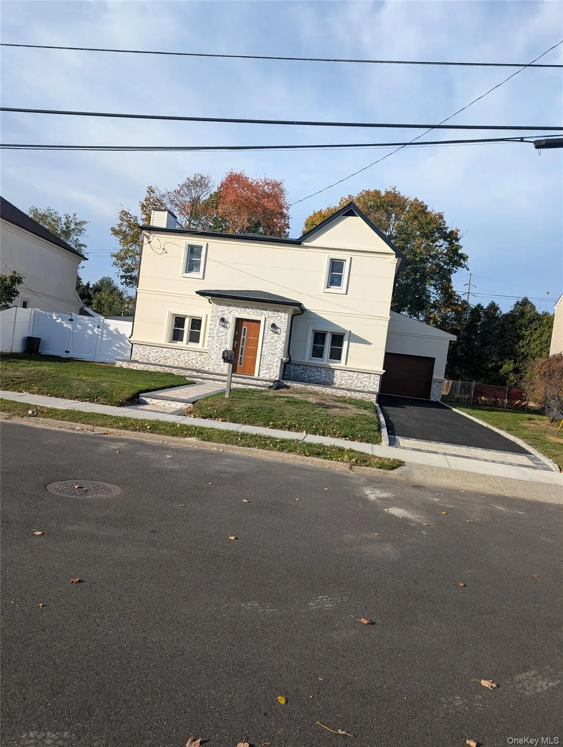 Colonial-style house with stone siding, a garage, and asphalt driveway Colonial-style house with stone siding, a garage, and asphalt driveway