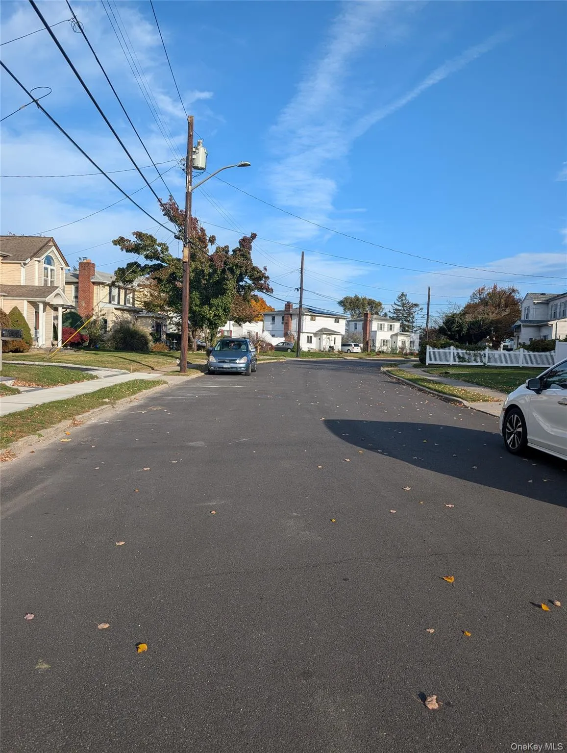 View of asphalt street with a residential view, street lights, curbs, and sidewalks View of asphalt street with a residential view, street lights, curbs, and sidewalks