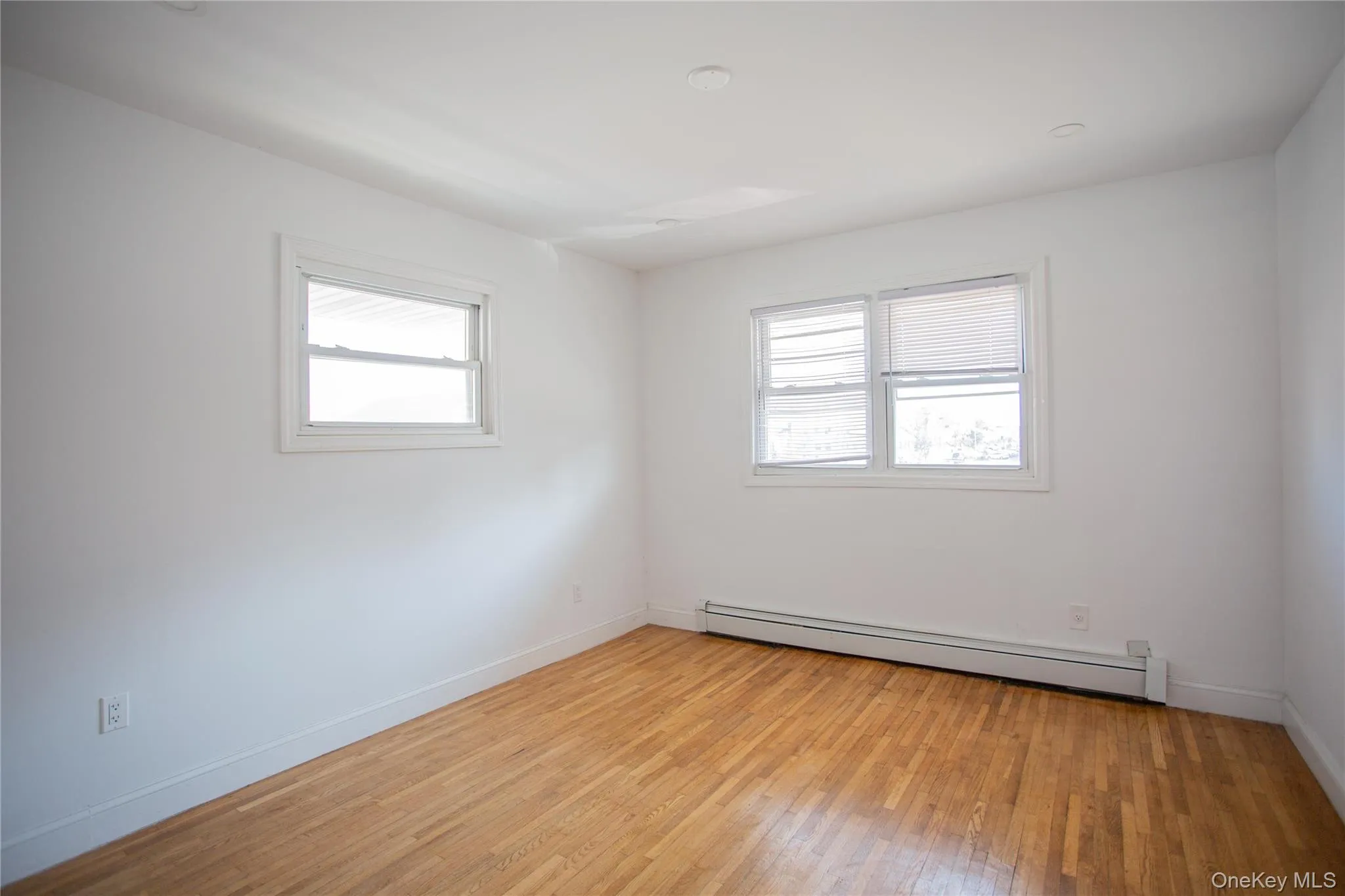 Empty room featuring a baseboard radiator and light wood-type flooring Empty room featuring a baseboard radiator and light wood-type flooring