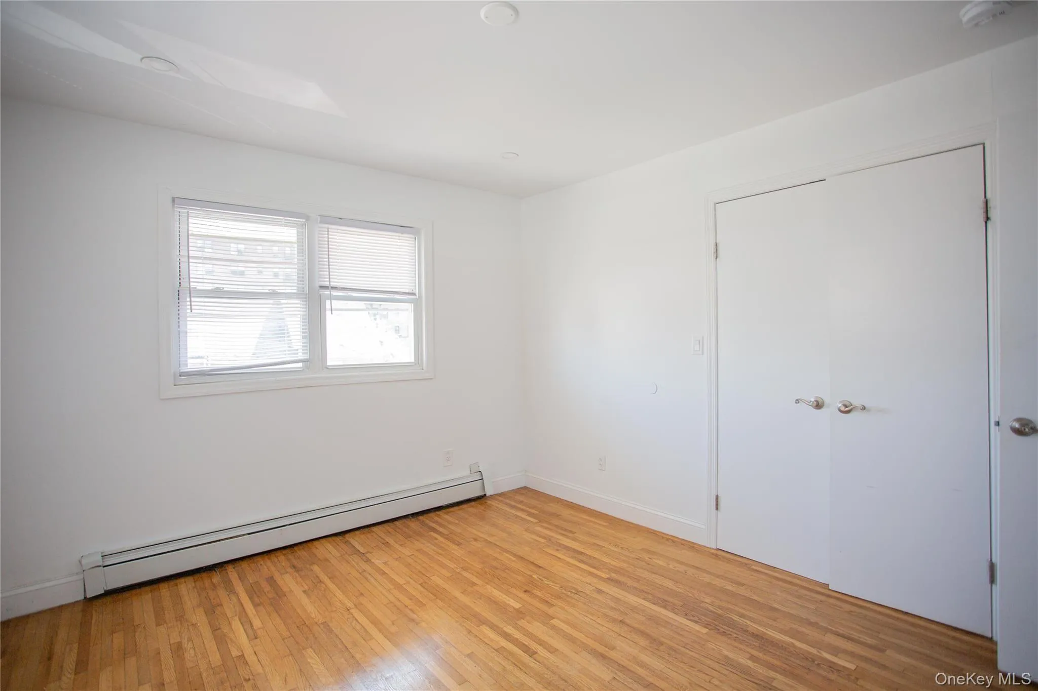 Unfurnished room with a baseboard radiator and light wood-style floors Unfurnished room with a baseboard radiator and light wood-style floors