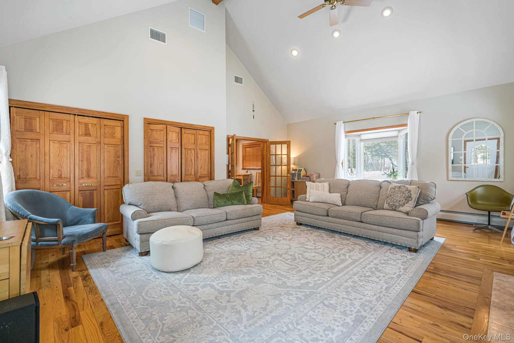 Living area featuring high vaulted ceiling, recessed lighting, ceiling fan, wood finished floors, and baseboard heating Living area featuring high vaulted ceiling, recessed lighting, ceiling fan, wood finished floors, and baseboard heating