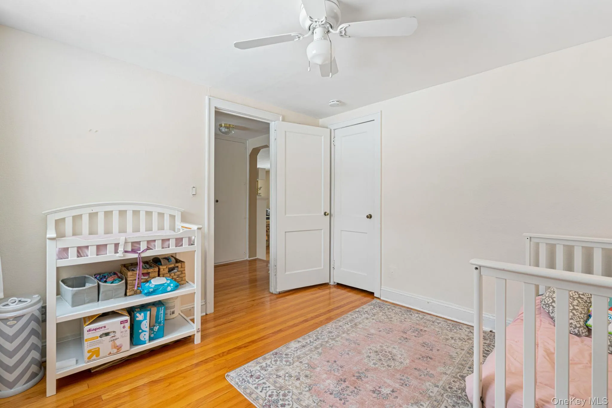 Bedroom with a crib, light wood-style floors, and ceiling fan Bedroom with a crib, light wood-style floors, and ceiling fan