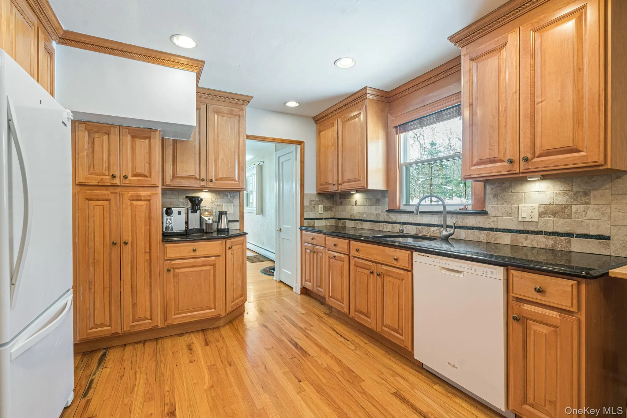 Kitchen featuring white appliances, dark stone countertops, tasteful backsplash, light wood-type flooring, and recessed lighting Kitchen featuring white appliances, dark stone countertops, tasteful backsplash, light wood-type flooring, and recessed lighting
