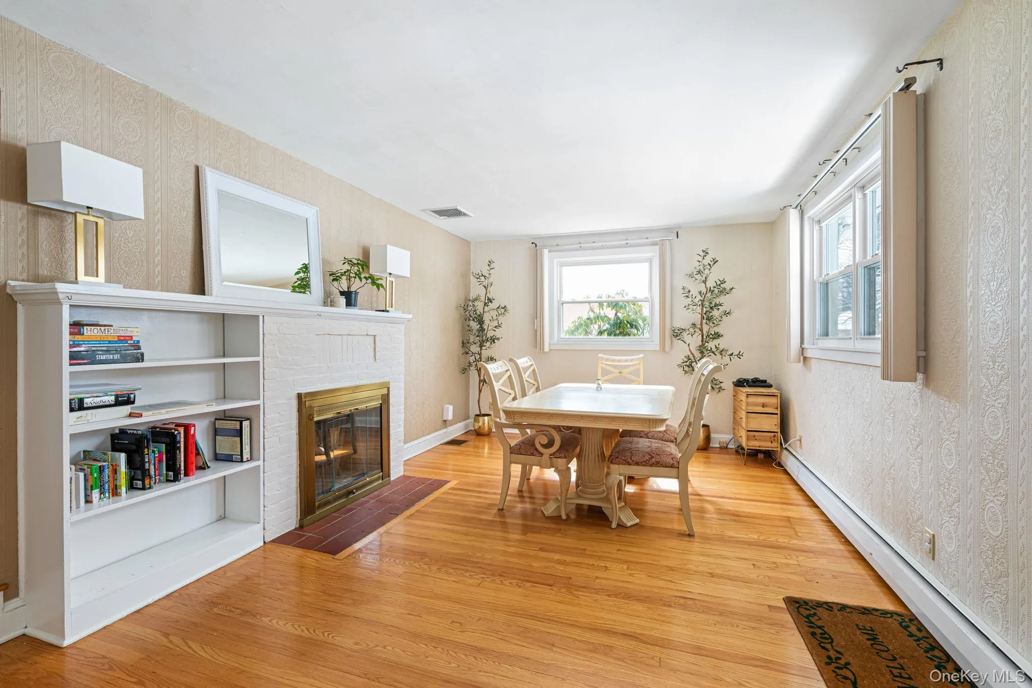 Dining room with a baseboard heating unit, light wood-type flooring, and a fireplace Dining room with a baseboard heating unit, light wood-type flooring, and a fireplace