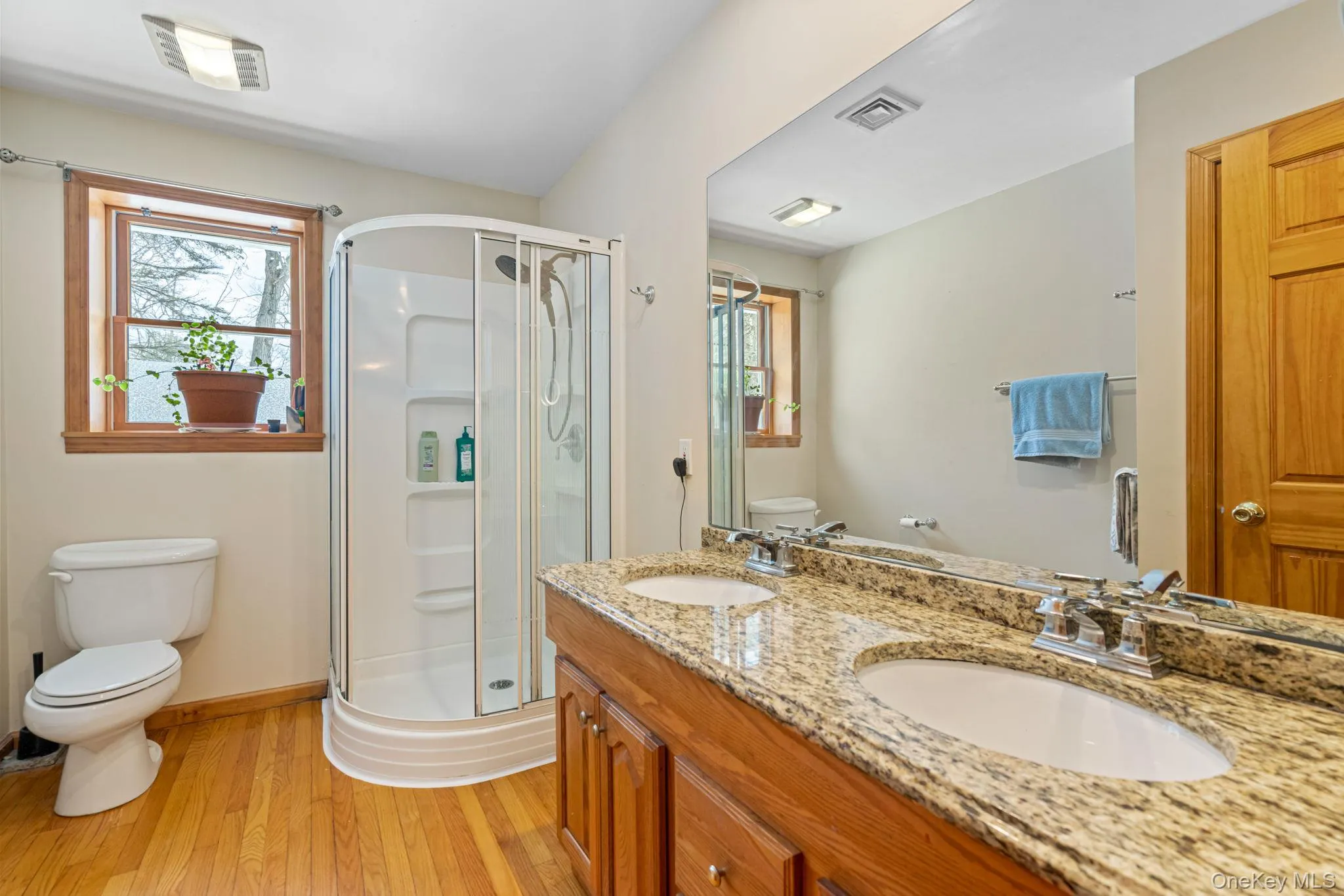 Full bath with light wood-style flooring, a shower stall, and double vanity Full bath with light wood-style flooring, a shower stall, and double vanity