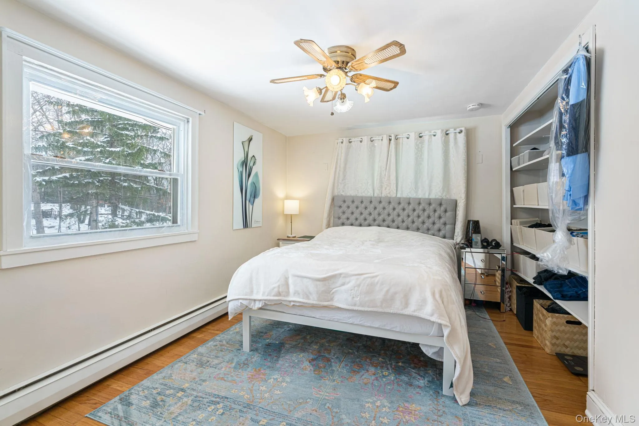 Bedroom featuring a baseboard radiator, light wood-style flooring, and ceiling fan Bedroom featuring a baseboard radiator, light wood-style flooring, and ceiling fan