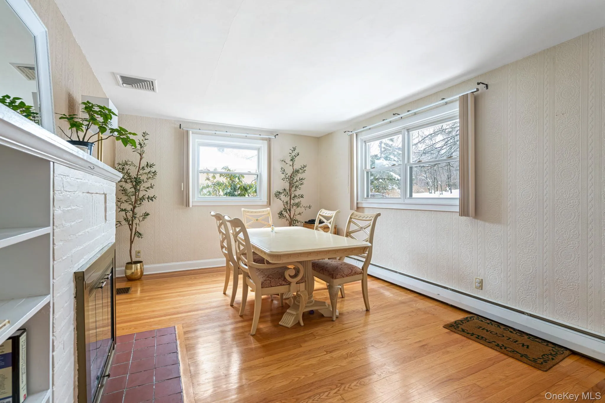 Dining area with light wood-type flooring, baseboard heating, and a fireplace with flush hearth Dining area with light wood-type flooring, baseboard heating, and a fireplace with flush hearth