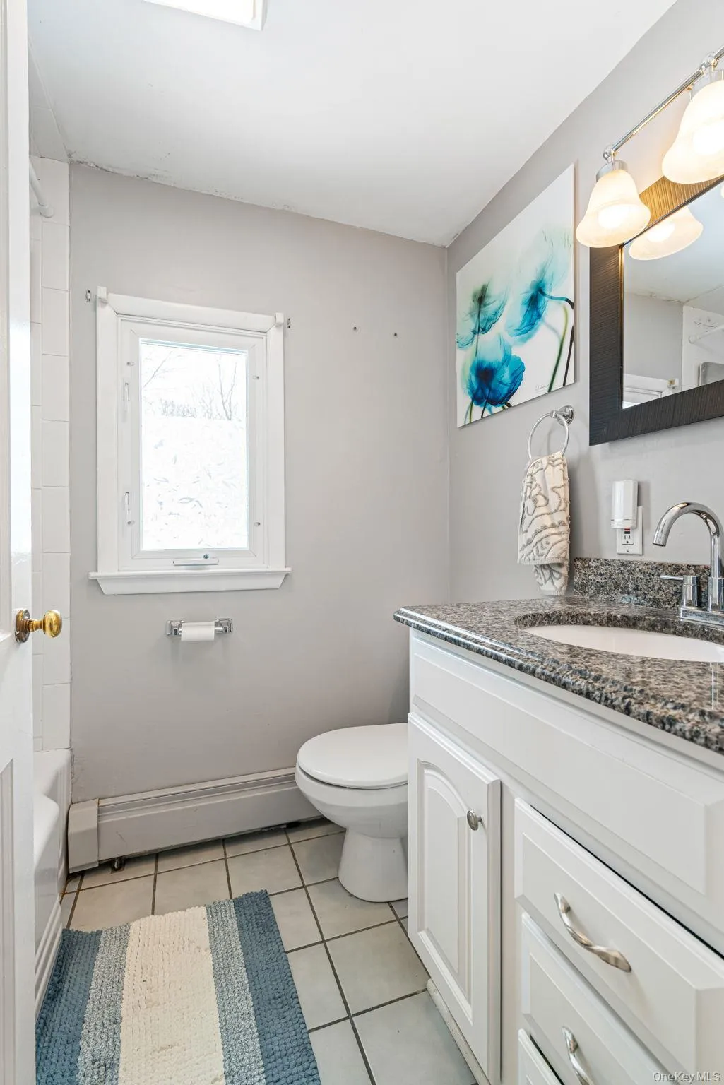 Bathroom featuring vanity, light tile patterned floors, a baseboard heating unit, and shower / tub combination Bathroom featuring vanity, light tile patterned floors, a baseboard heating unit, and shower / tub combination