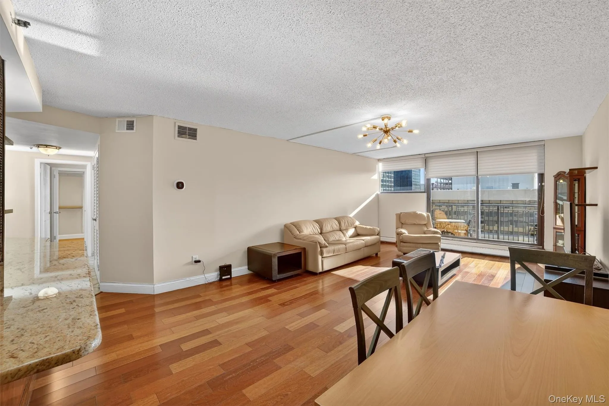 Dining space with light wood finished floors, a textured ceiling, and a chandelier Dining space with light wood finished floors, a textured ceiling, and a chandelier