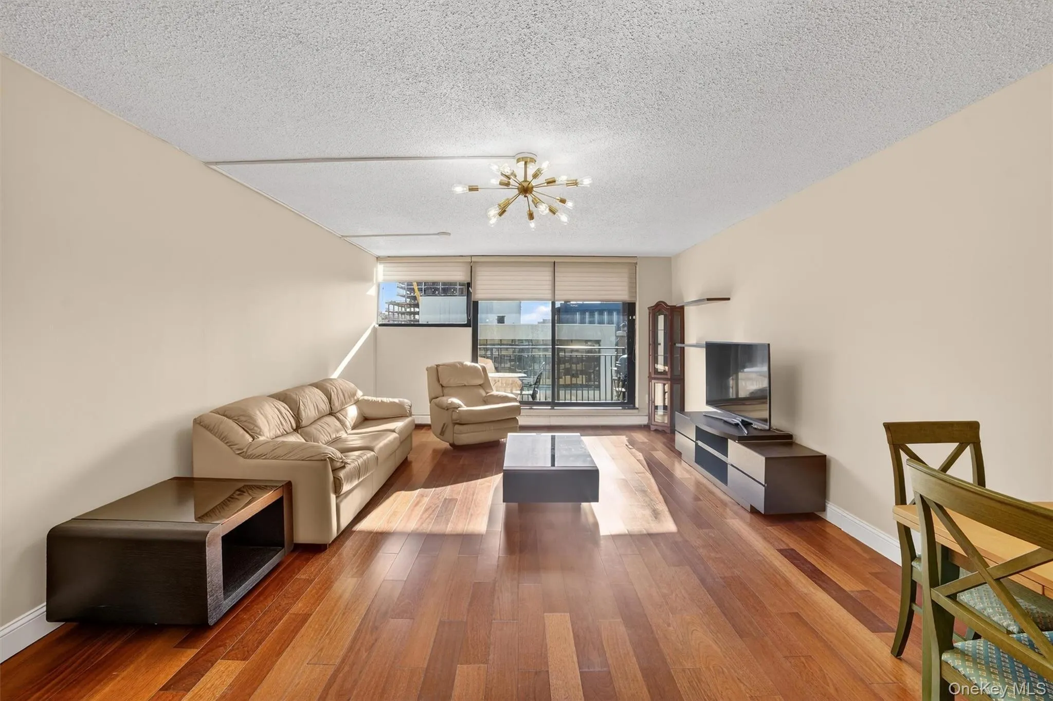 Living room featuring a chandelier, hardwood / wood-style flooring, expansive windows, and a textured ceiling Living room featuring a chandelier, hardwood / wood-style flooring, expansive windows, and a textured ceiling