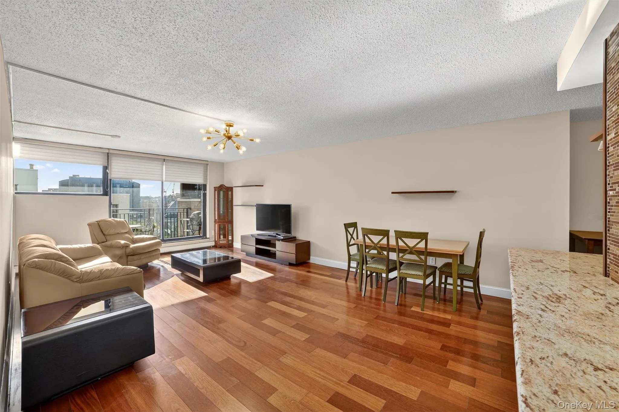 Living area with a textured ceiling, wood finished floors, and a chandelier Living area with a textured ceiling, wood finished floors, and a chandelier
