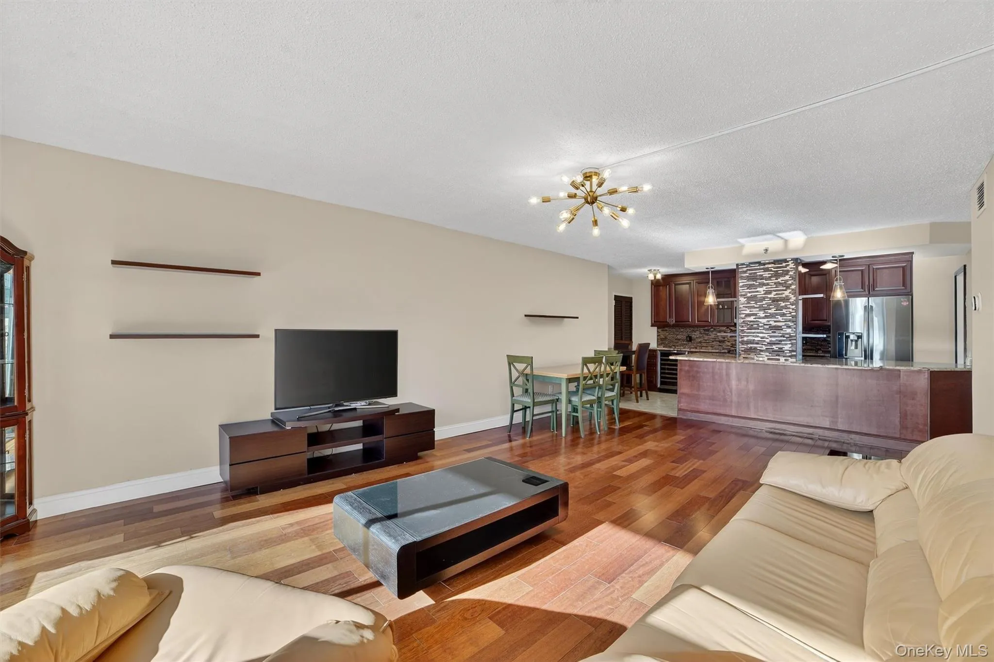 Living room with light wood finished floors, a textured ceiling, and a chandelier Living room with light wood finished floors, a textured ceiling, and a chandelier