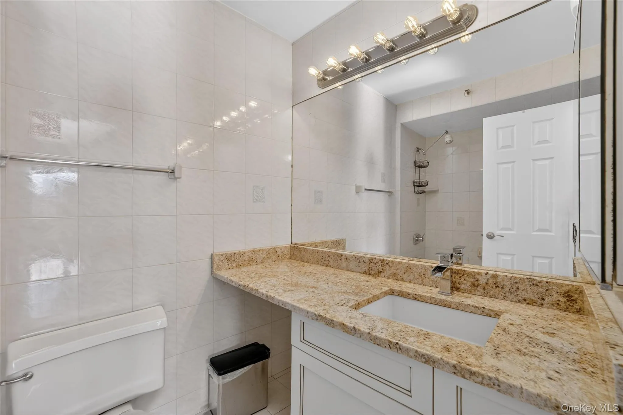Bathroom featuring tile walls, vanity, and a tile shower Bathroom featuring tile walls, vanity, and a tile shower