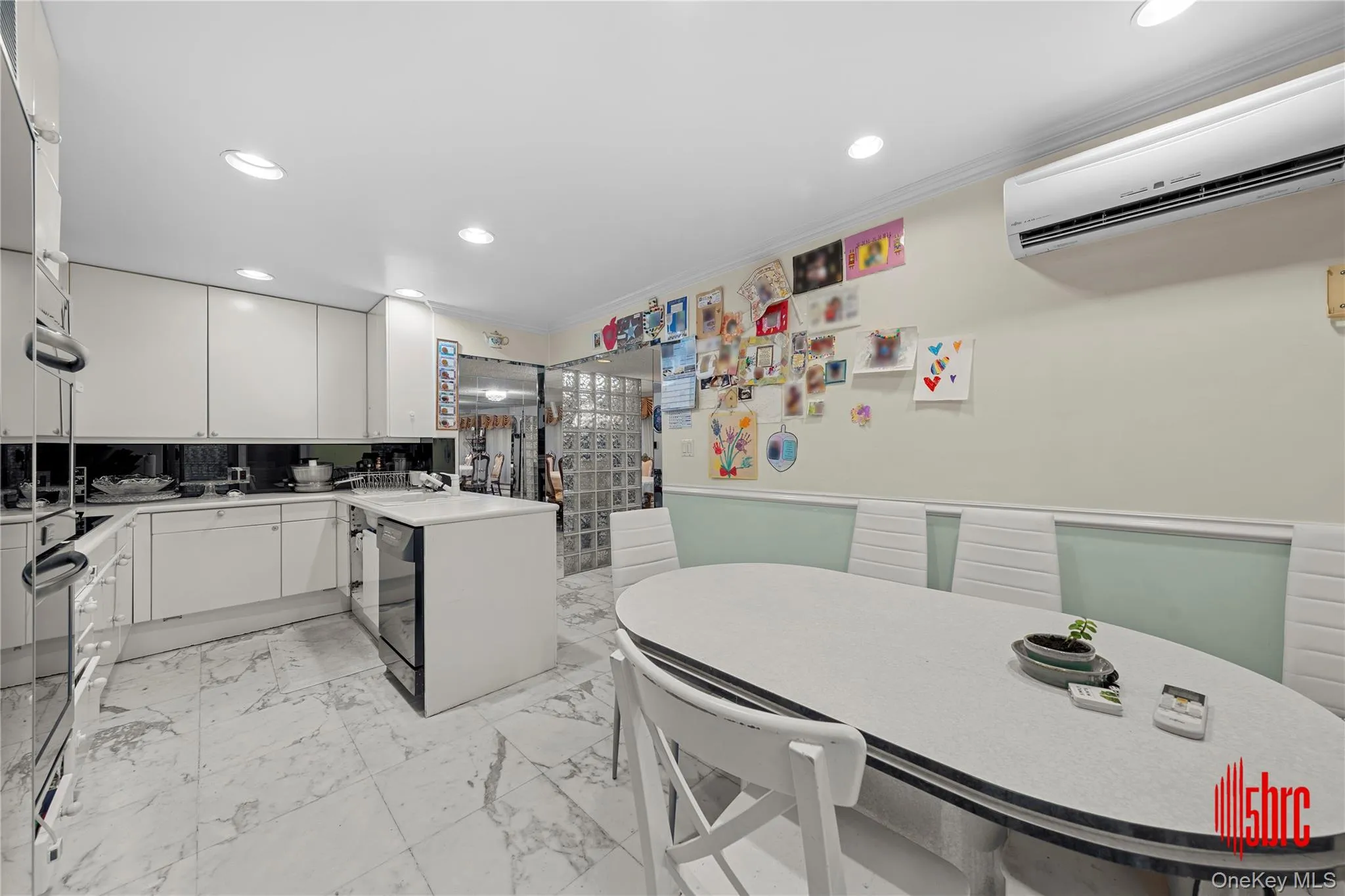 Kitchen with crown molding, recessed lighting, wainscoting, a peninsula, and white cabinetry Kitchen with crown molding, recessed lighting, wainscoting, a peninsula, and white cabinetry