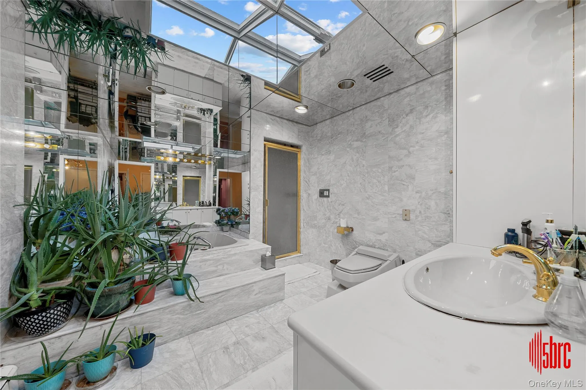 Bathroom with tile walls, a garden tub, vanity, and a skylight Bathroom with tile walls, a garden tub, vanity, and a skylight