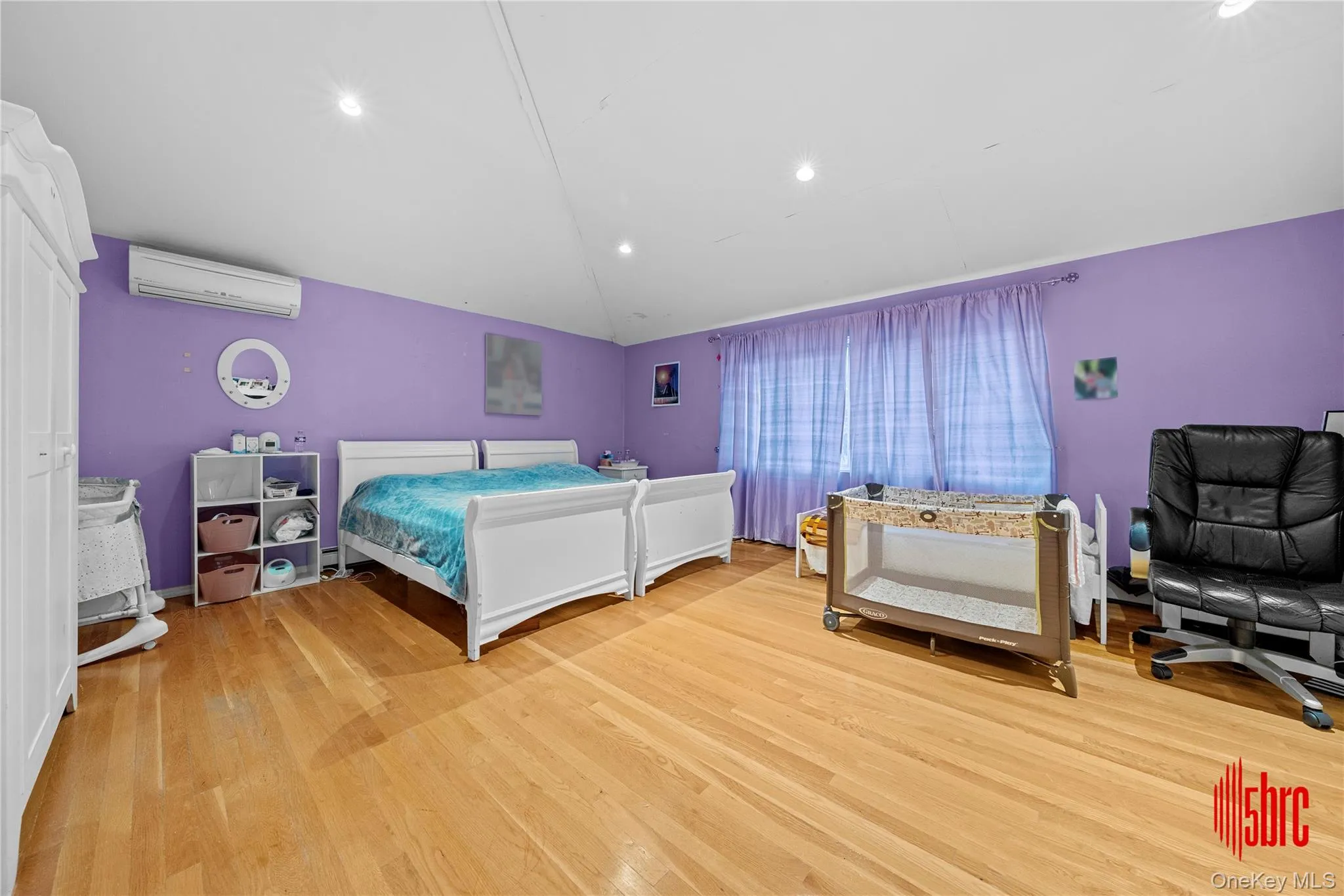 Bedroom featuring vaulted ceiling, light wood-style flooring, recessed lighting, and a wall mounted air conditioner Bedroom featuring vaulted ceiling, light wood-style flooring, recessed lighting, and a wall mounted air conditioner