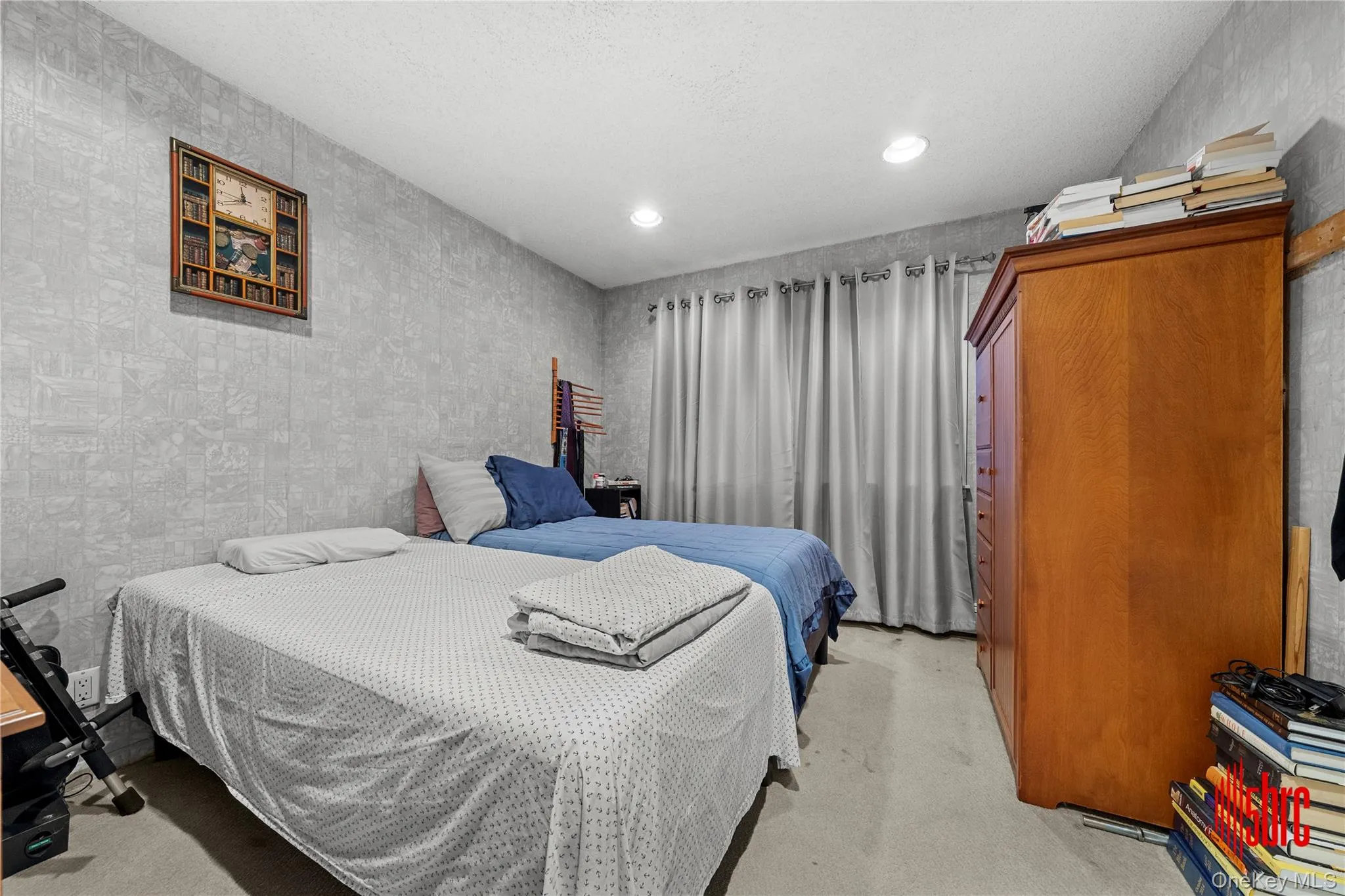 Bedroom featuring light colored carpet, recessed lighting, a textured ceiling, and wallpapered walls Bedroom featuring light colored carpet, recessed lighting, a textured ceiling, and wallpapered walls