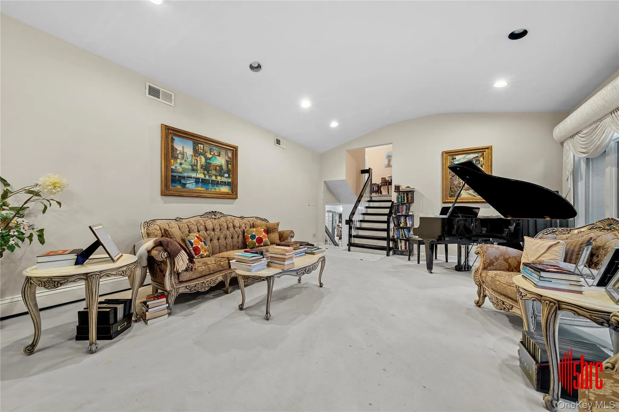Living room featuring lofted ceiling, stairs, and recessed lighting Living room featuring lofted ceiling, stairs, and recessed lighting