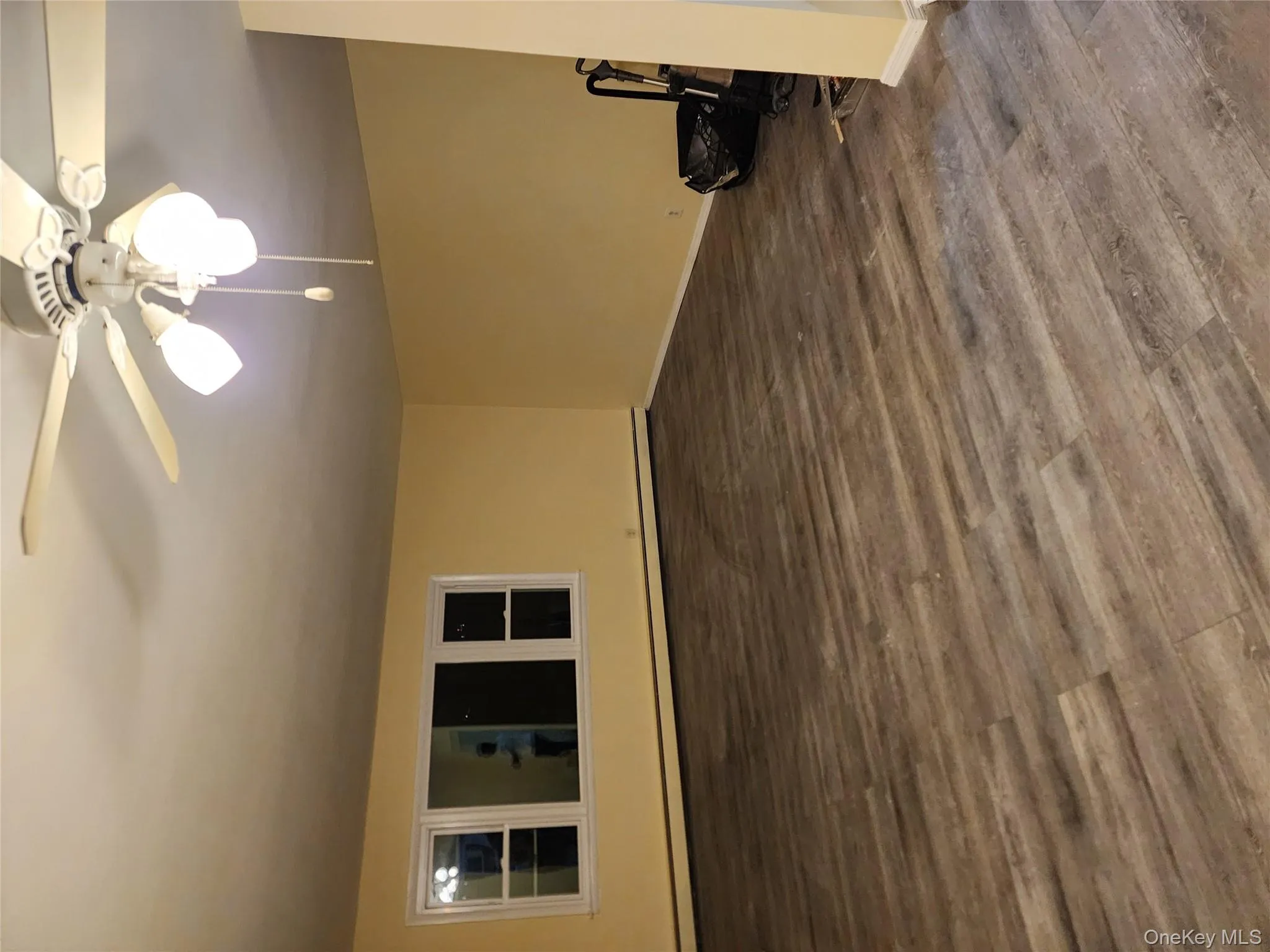 Empty room featuring a ceiling fan, dark wood-style flooring, and baseboard heating Empty room featuring a ceiling fan, dark wood-style flooring, and baseboard heating