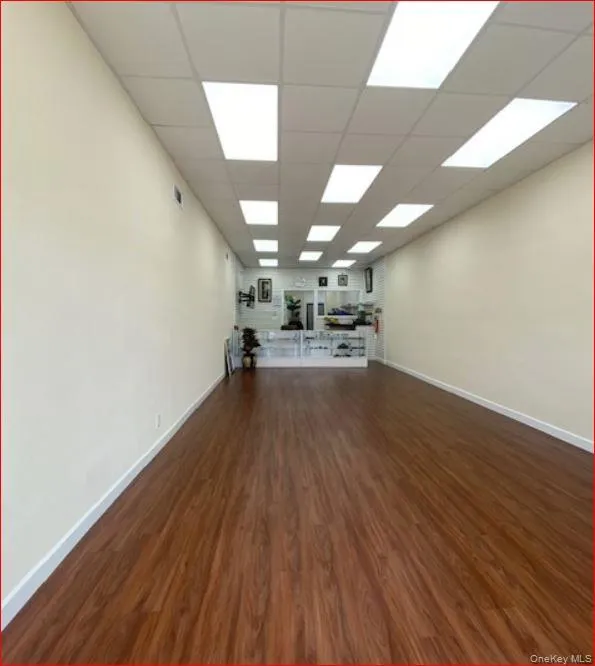 Unfurnished living room with dark wood-type flooring and a drop ceiling Unfurnished living room with dark wood-type flooring and a drop ceiling