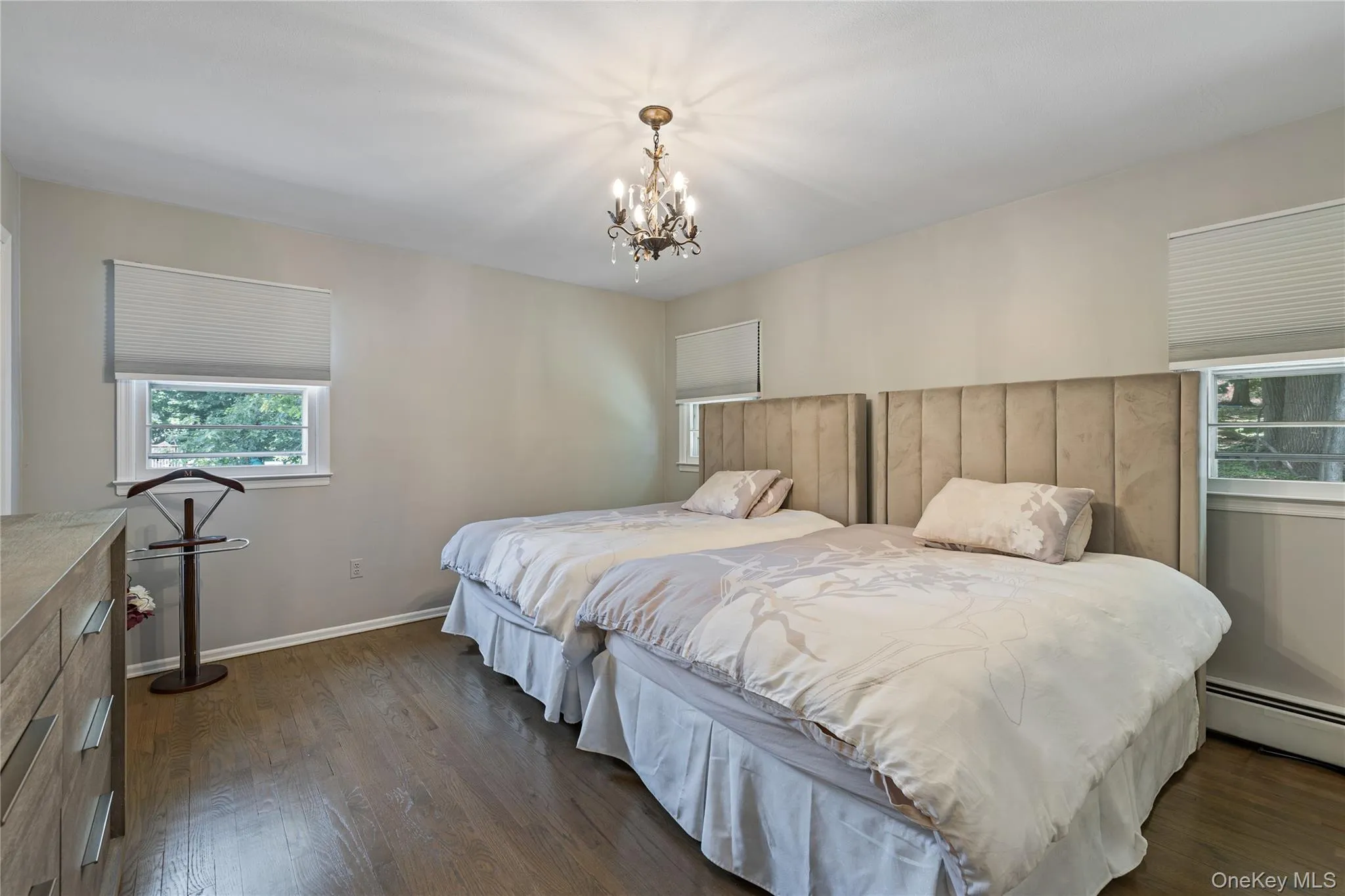 Bedroom featuring dark wood-style floors, a chandelier, and a baseboard heating unit Bedroom featuring dark wood-style floors, a chandelier, and a baseboard heating unit