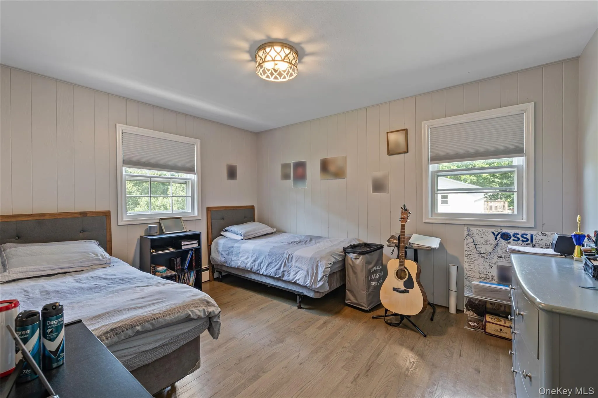 Bedroom with light wood finished floors, multiple windows, and wooden walls Bedroom with light wood finished floors, multiple windows, and wooden walls