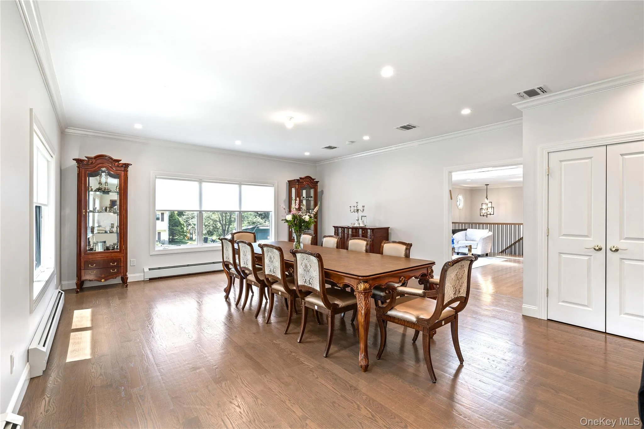 Dining space featuring a baseboard heating unit, wood finished floors, crown molding, recessed lighting, and a chandelier Dining space featuring a baseboard heating unit, wood finished floors, crown molding, recessed lighting, and a chandelier