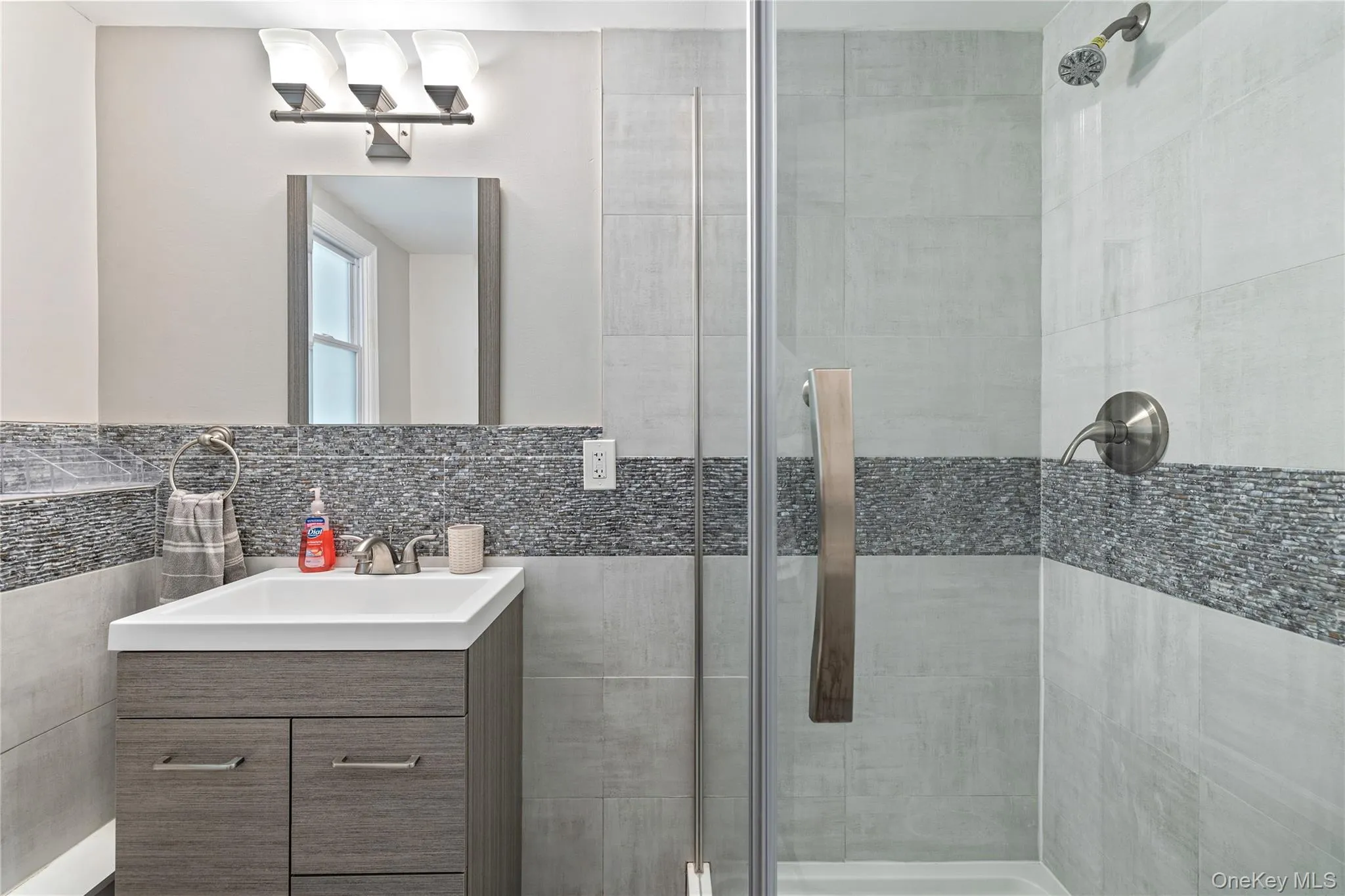 Bathroom featuring vanity, a stall shower, and tile walls Bathroom featuring vanity, a stall shower, and tile walls
