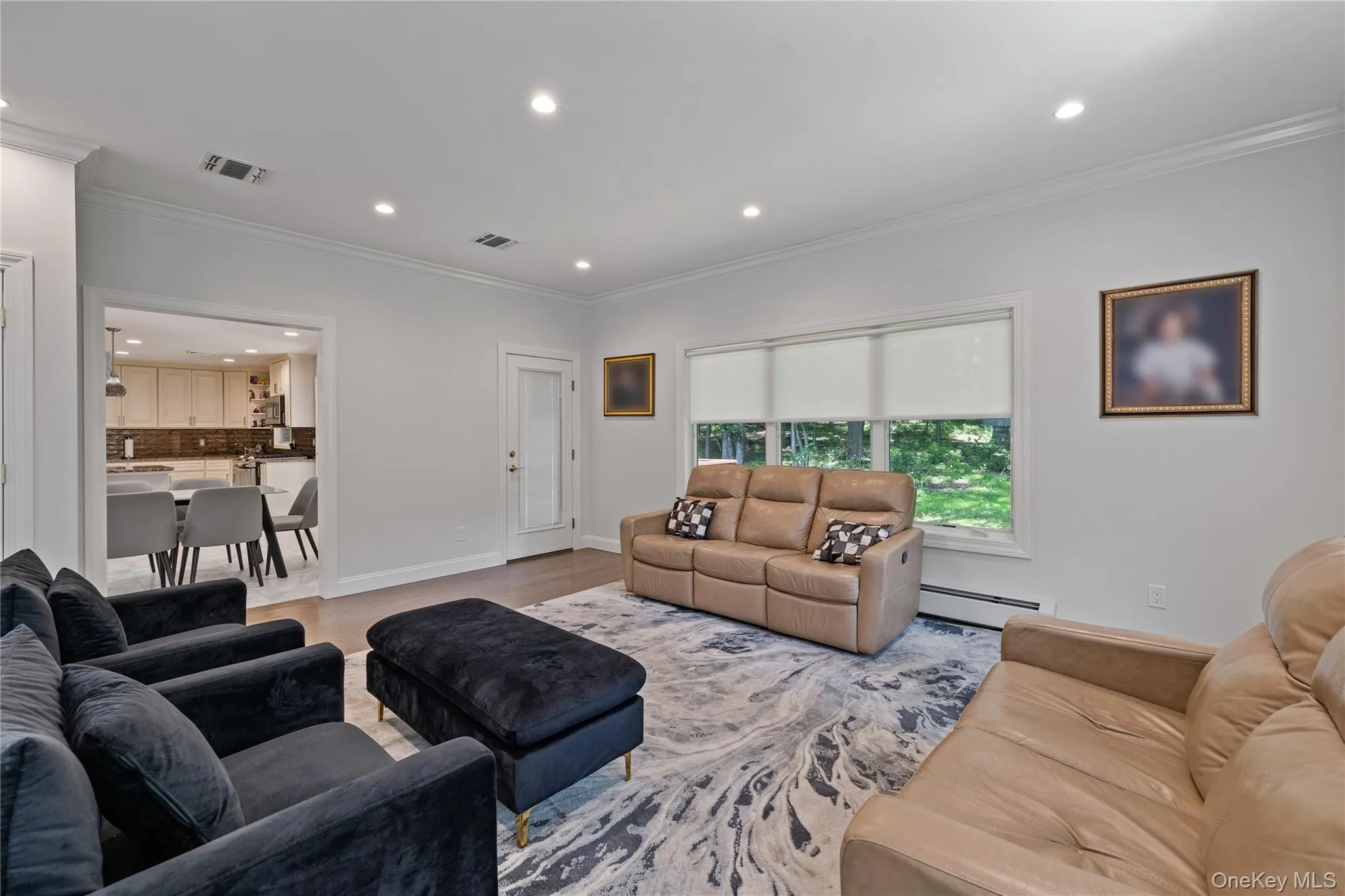 Living room featuring recessed lighting, ornamental molding, a baseboard heating unit, and wood finished floors Living room featuring recessed lighting, ornamental molding, a baseboard heating unit, and wood finished floors