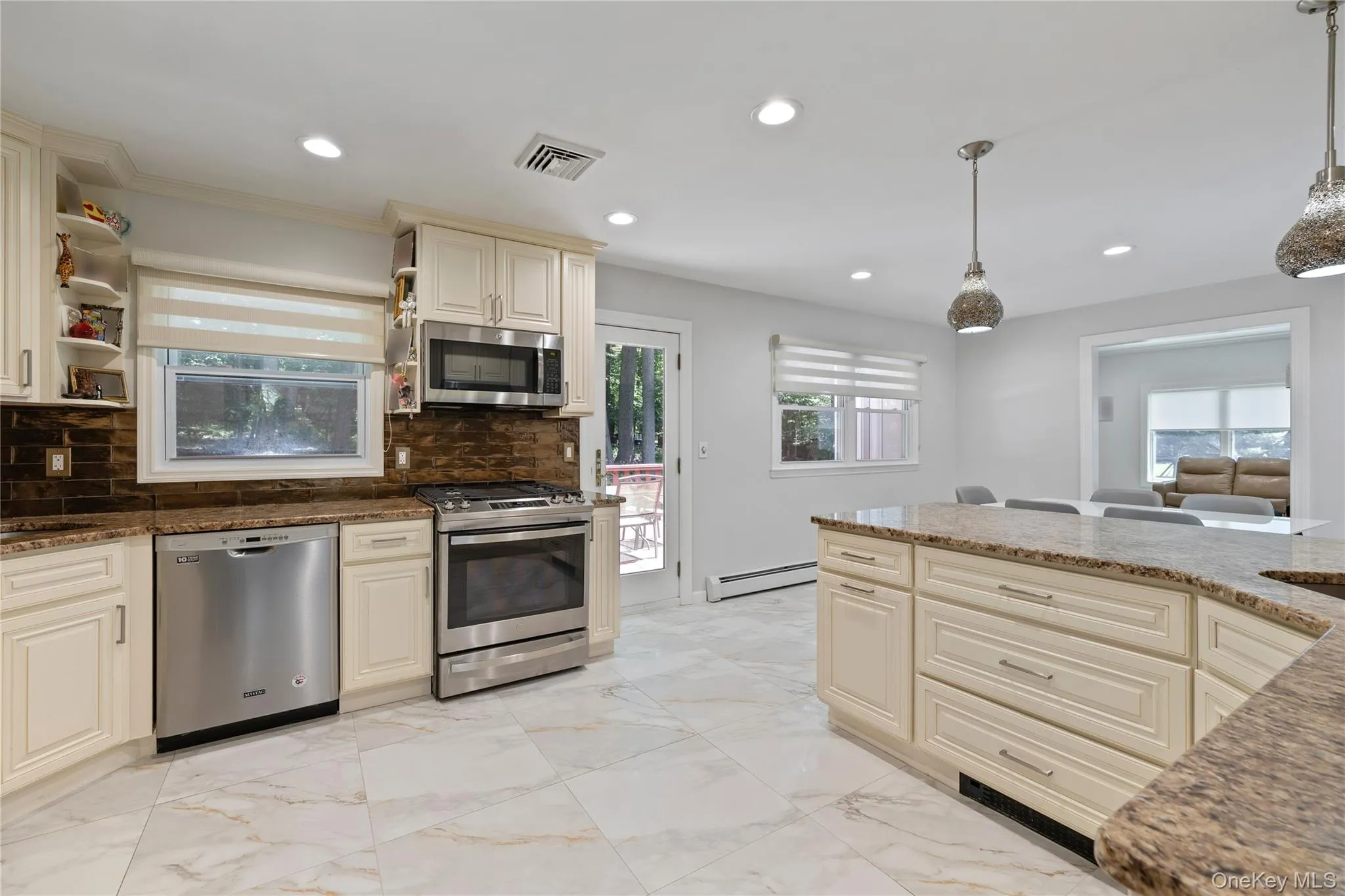 Kitchen featuring cream cabinetry, light marble finish flooring, stainless steel appliances, backsplash, and recessed lighting Kitchen featuring cream cabinetry, light marble finish flooring, stainless steel appliances, backsplash, and recessed lighting