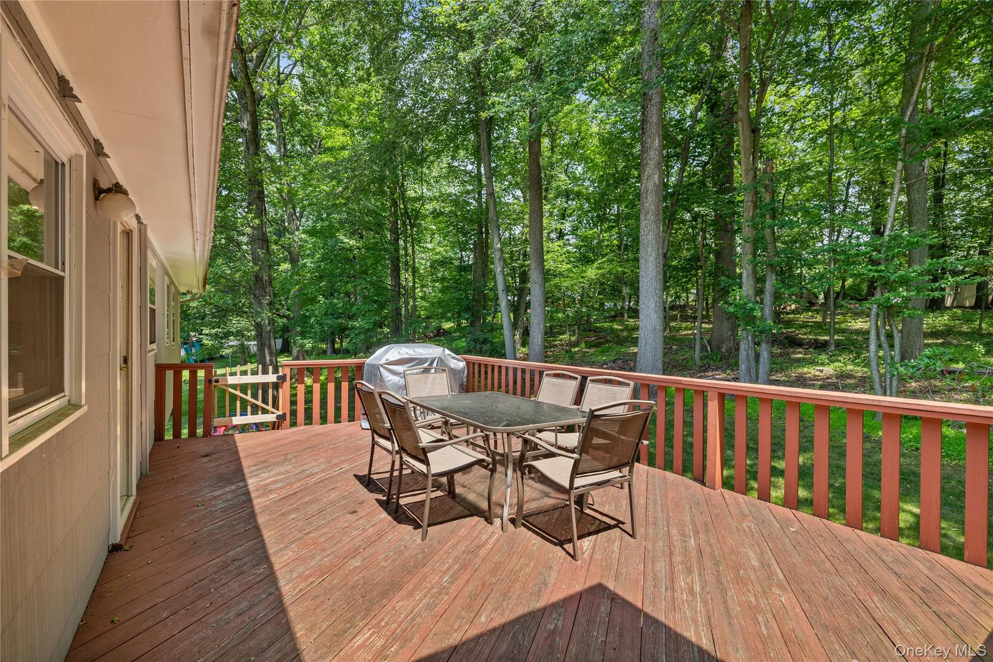 Wooden terrace featuring outdoor dining area, view of wooded area, and a grill Wooden terrace featuring outdoor dining area, view of wooded area, and a grill