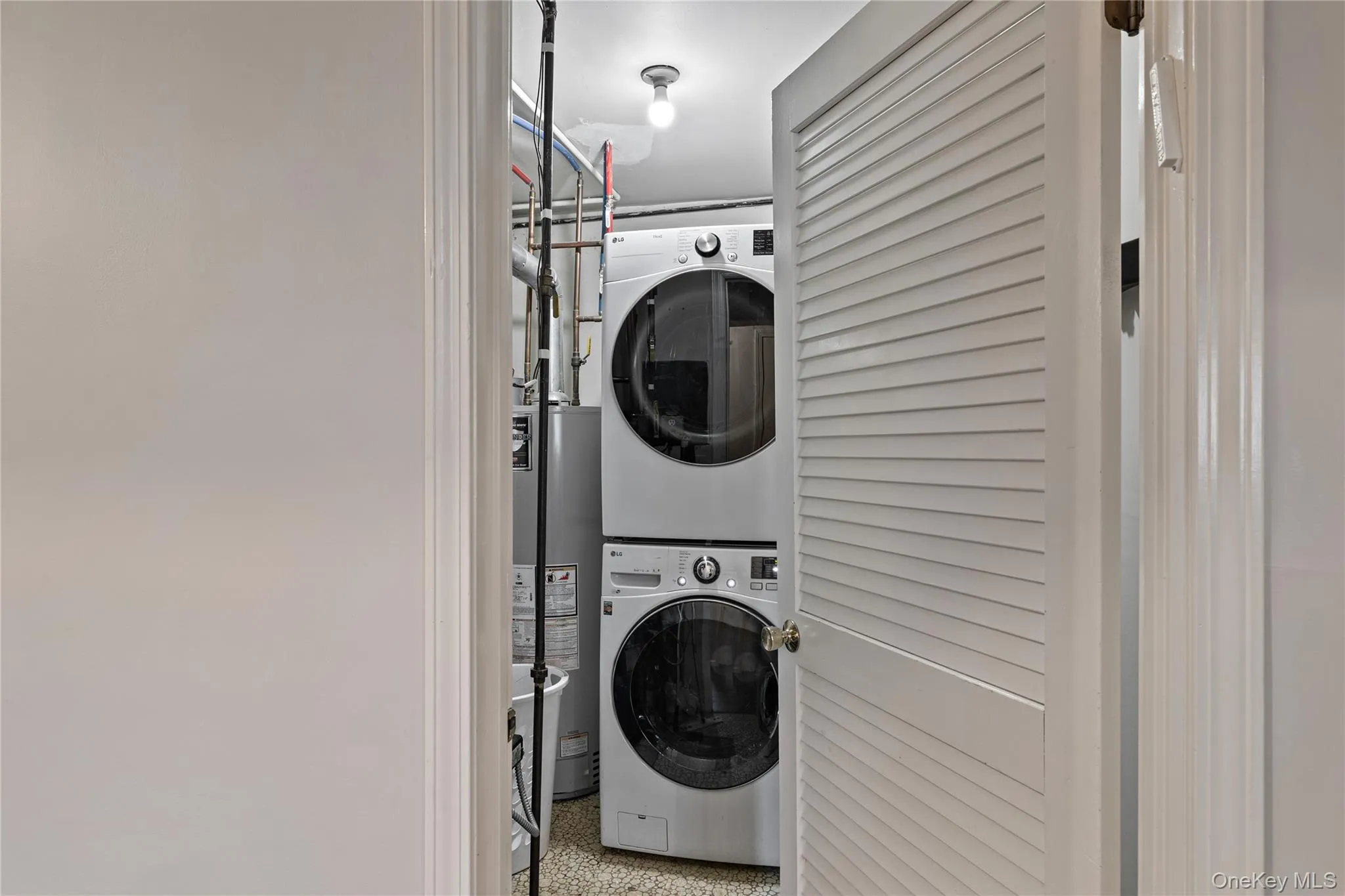 Laundry area featuring stacked washing machine and dryer and water heater Laundry area featuring stacked washing machine and dryer and water heater