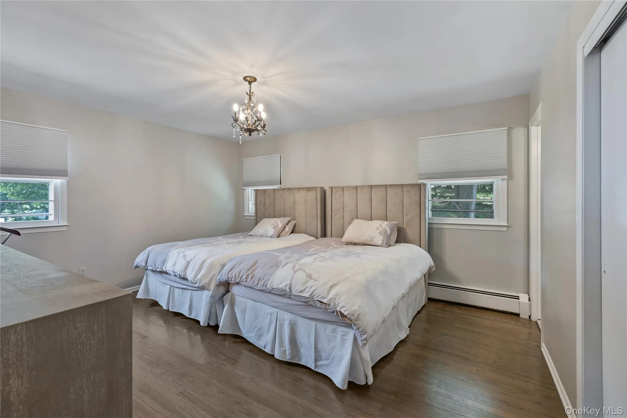 Bedroom featuring a baseboard radiator, wood finished floors, and a chandelier Bedroom featuring a baseboard radiator, wood finished floors, and a chandelier