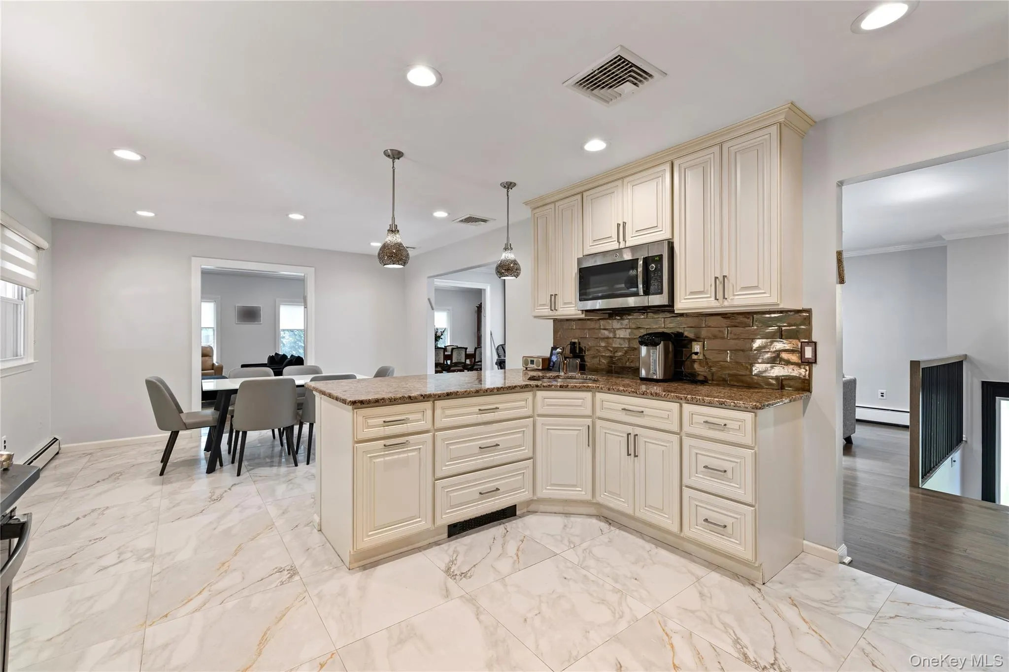 Kitchen featuring cream cabinets, pendant lighting, recessed lighting, dark stone countertops, and stainless steel microwave Kitchen featuring cream cabinets, pendant lighting, recessed lighting, dark stone countertops, and stainless steel microwave
