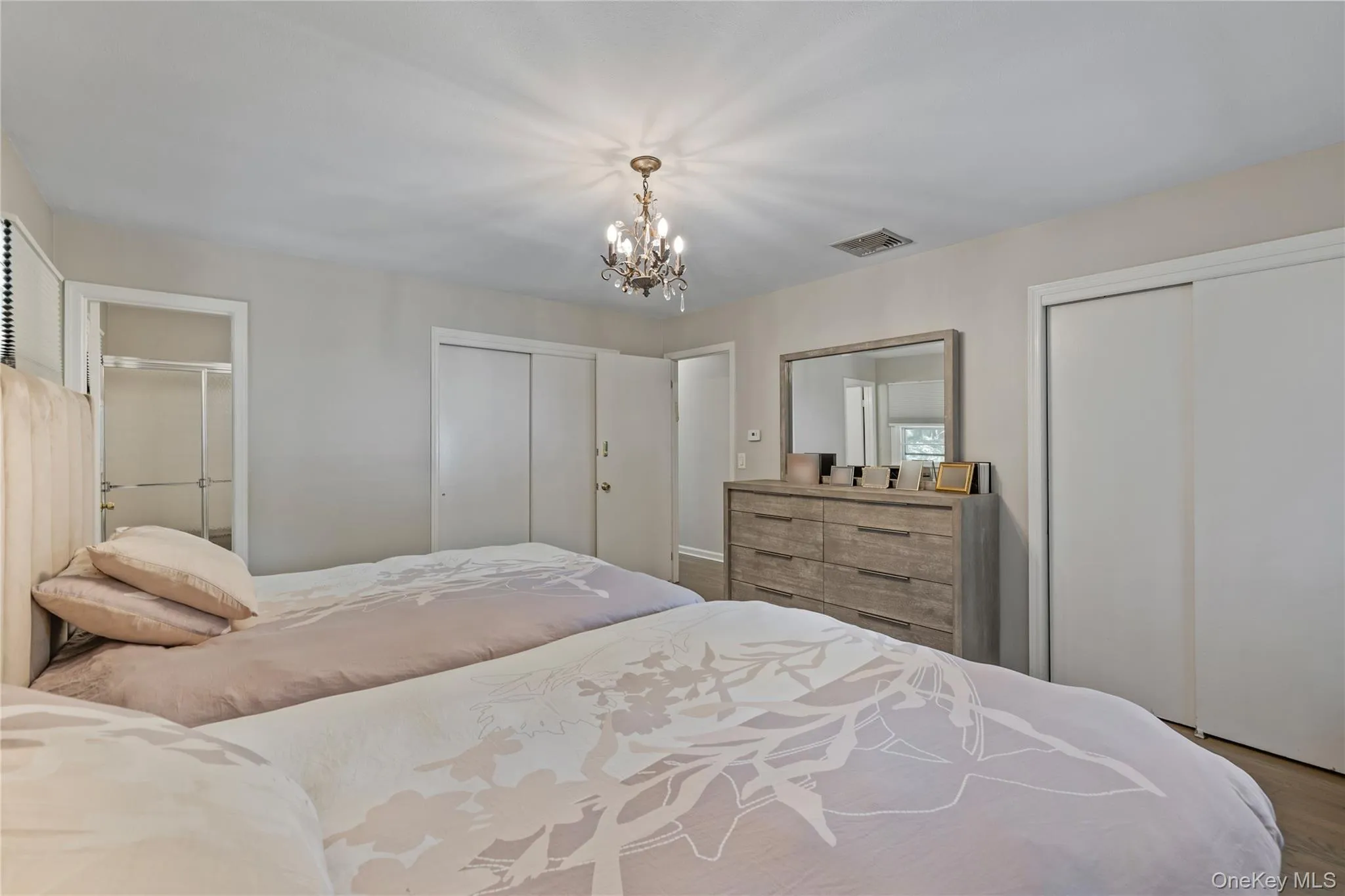 Bedroom featuring multiple closets, a chandelier, and wood finished floors Bedroom featuring multiple closets, a chandelier, and wood finished floors