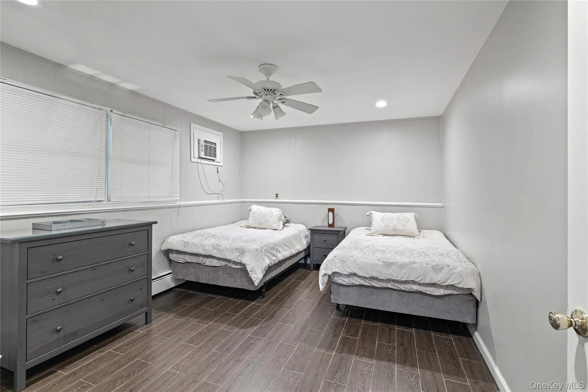 Bedroom with wood finish floors, recessed lighting, ceiling fan, a baseboard radiator, and an AC wall unit Bedroom with wood finish floors, recessed lighting, ceiling fan, a baseboard radiator, and an AC wall unit