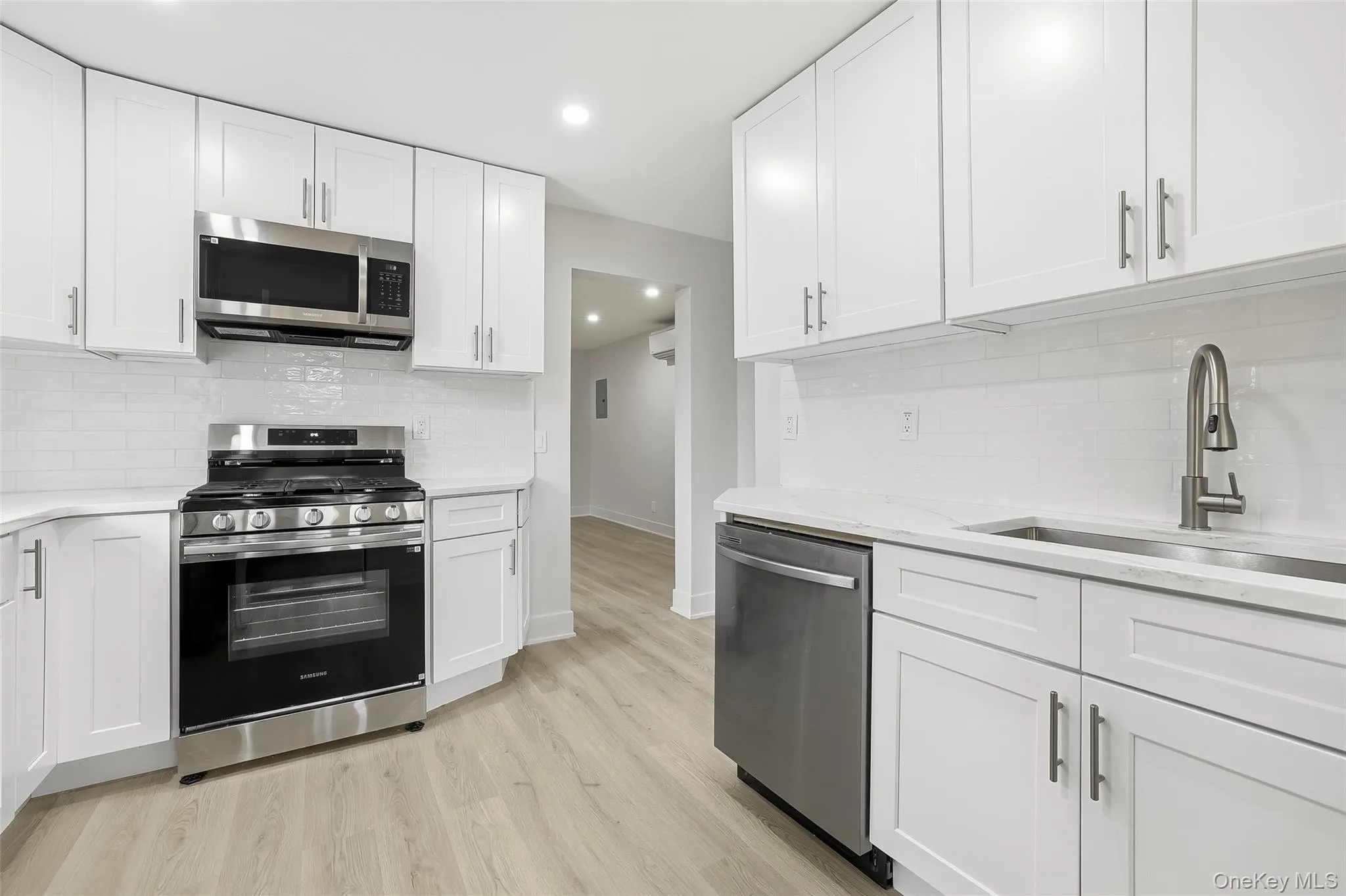 Kitchen with backsplash, stainless steel appliances, white cabinets, and recessed lighting Kitchen with backsplash, stainless steel appliances, white cabinets, and recessed lighting