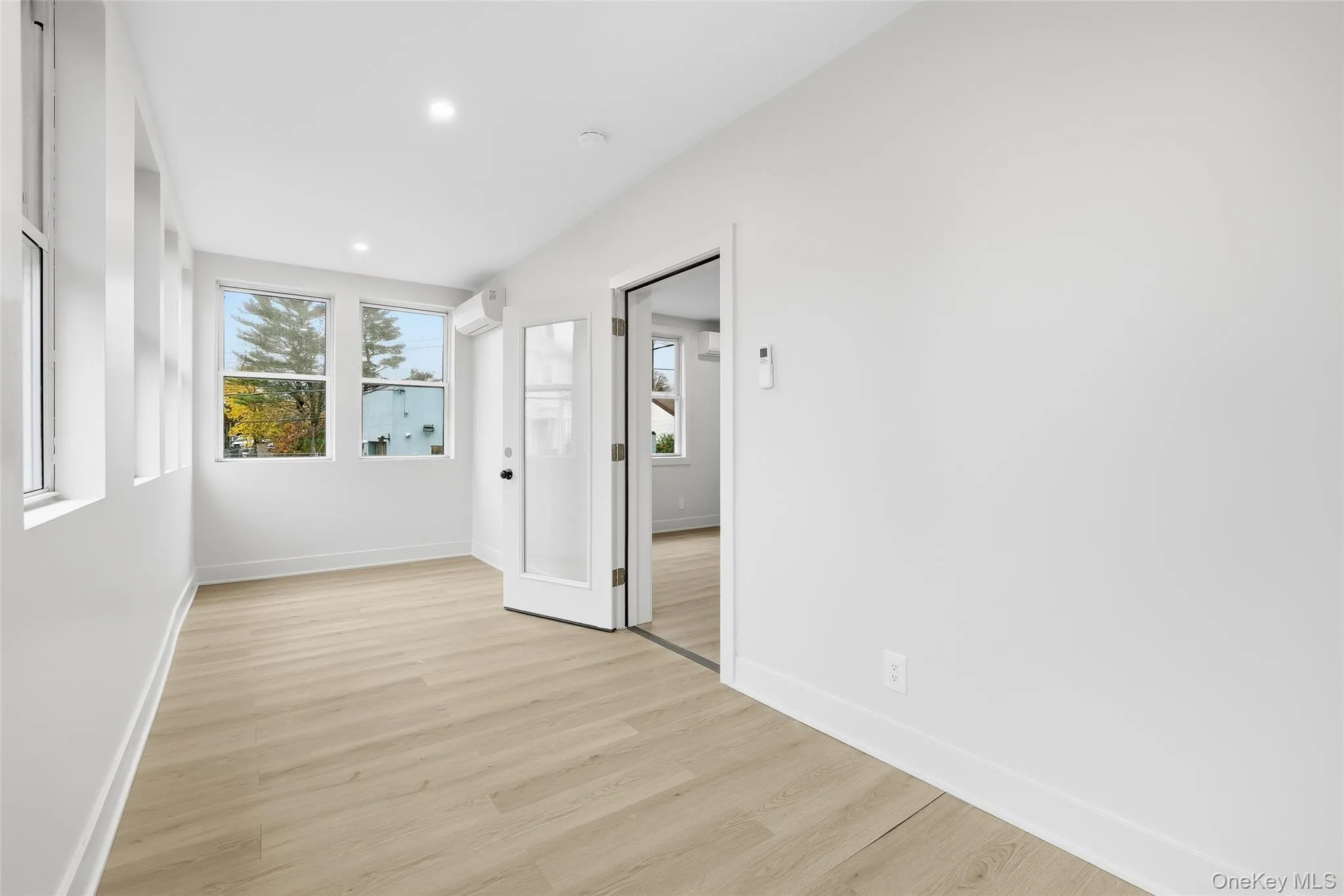 Unfurnished room with light wood-style flooring, recessed lighting, and an AC wall unit Unfurnished room with light wood-style flooring, recessed lighting, and an AC wall unit