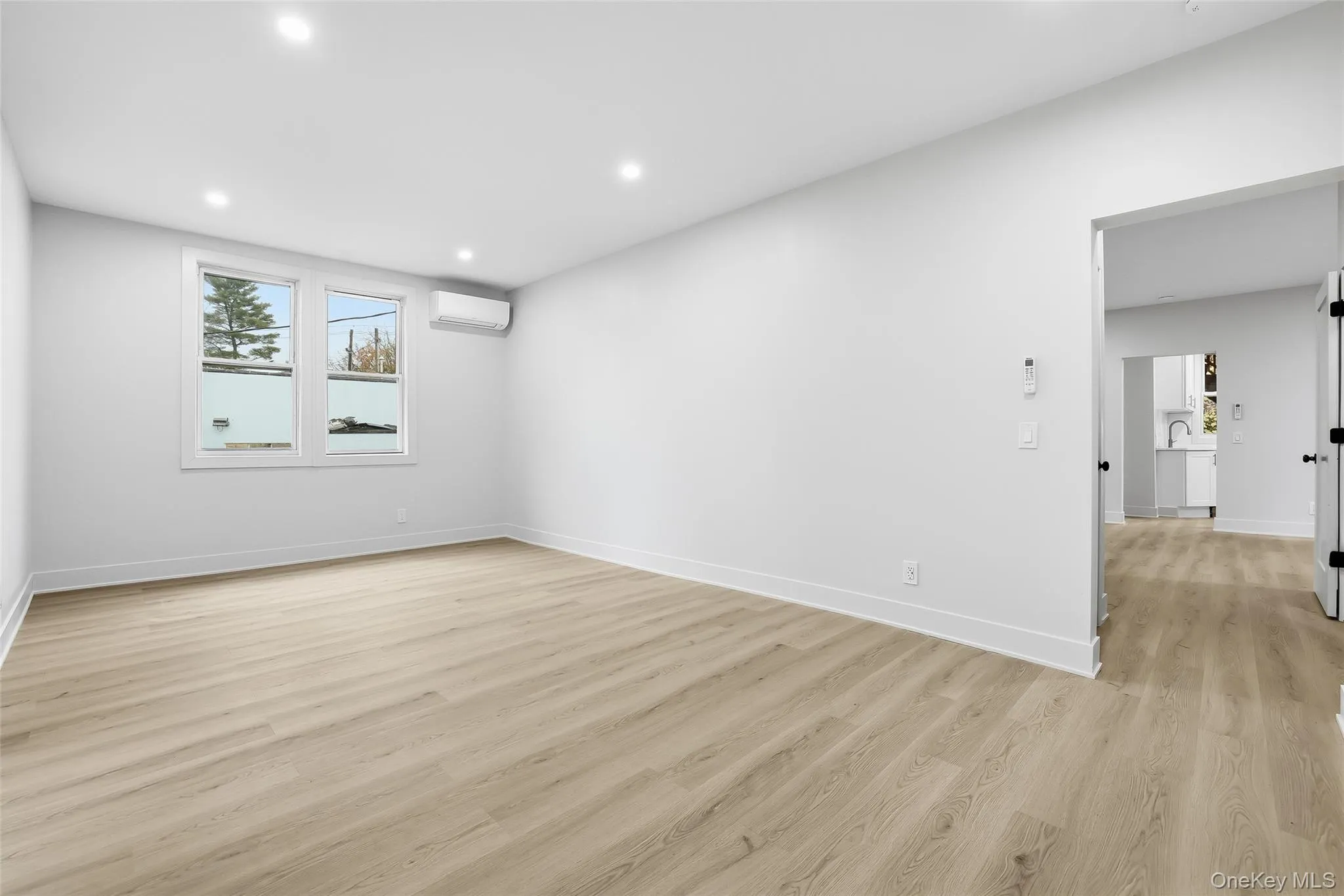Unfurnished room featuring light wood-style flooring, recessed lighting, and a wall mounted AC Unfurnished room featuring light wood-style flooring, recessed lighting, and a wall mounted AC