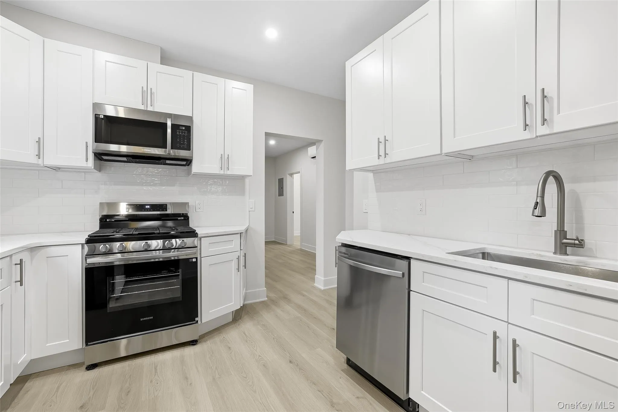 Kitchen with decorative backsplash, appliances with stainless steel finishes, white cabinetry, light wood-type flooring, and recessed lighting Kitchen with decorative backsplash, appliances with stainless steel finishes, white cabinetry, light wood-type flooring, and recessed lighting