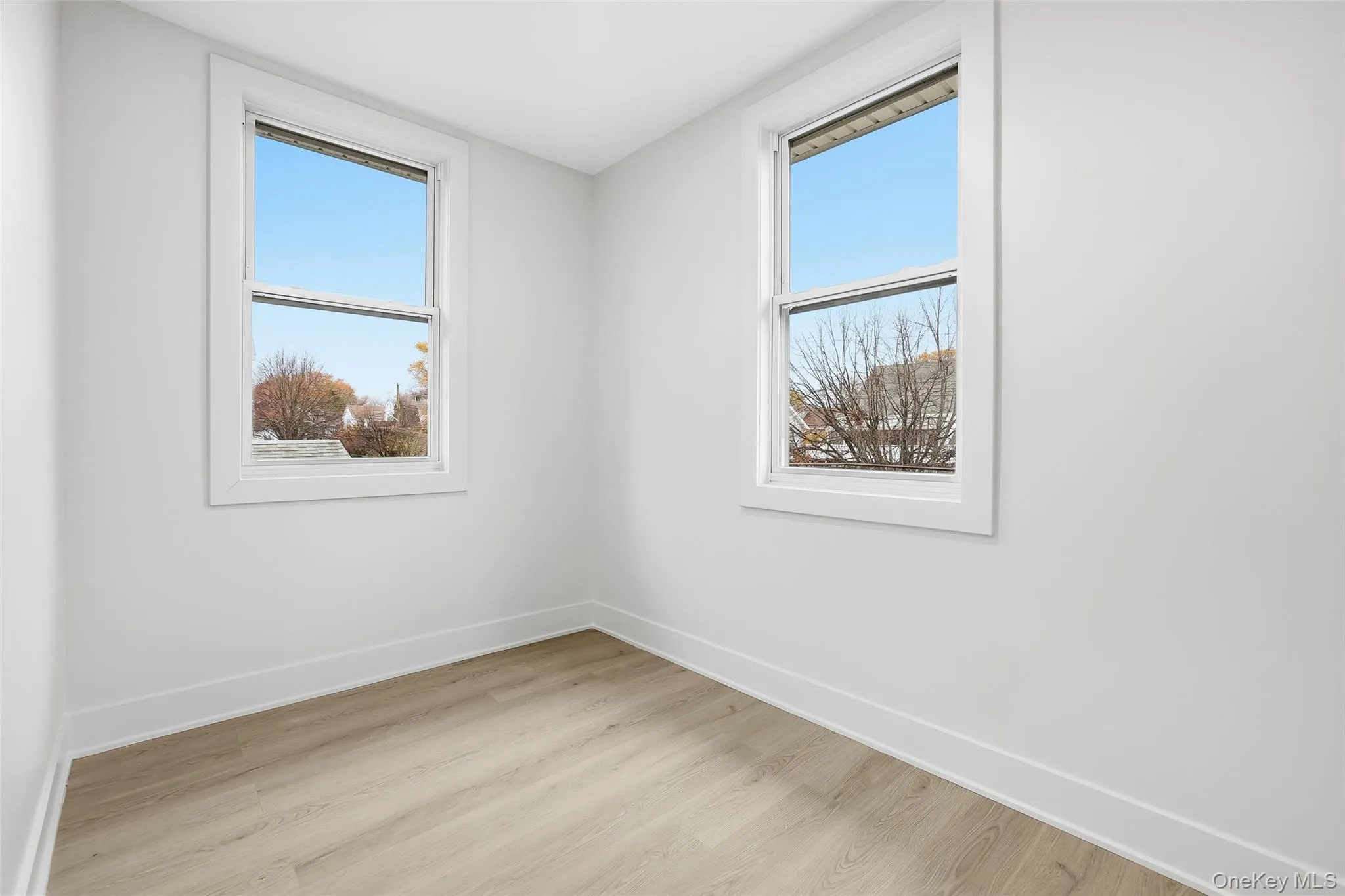 Empty room featuring wood finished floors and baseboards Empty room featuring wood finished floors and baseboards