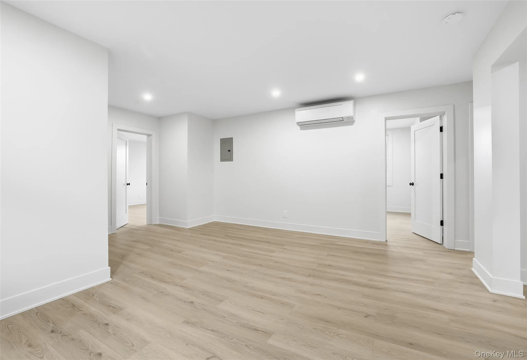 Spare room featuring light wood-type flooring, recessed lighting, electric panel, and a wall mounted AC Spare room featuring light wood-type flooring, recessed lighting, electric panel, and a wall mounted AC