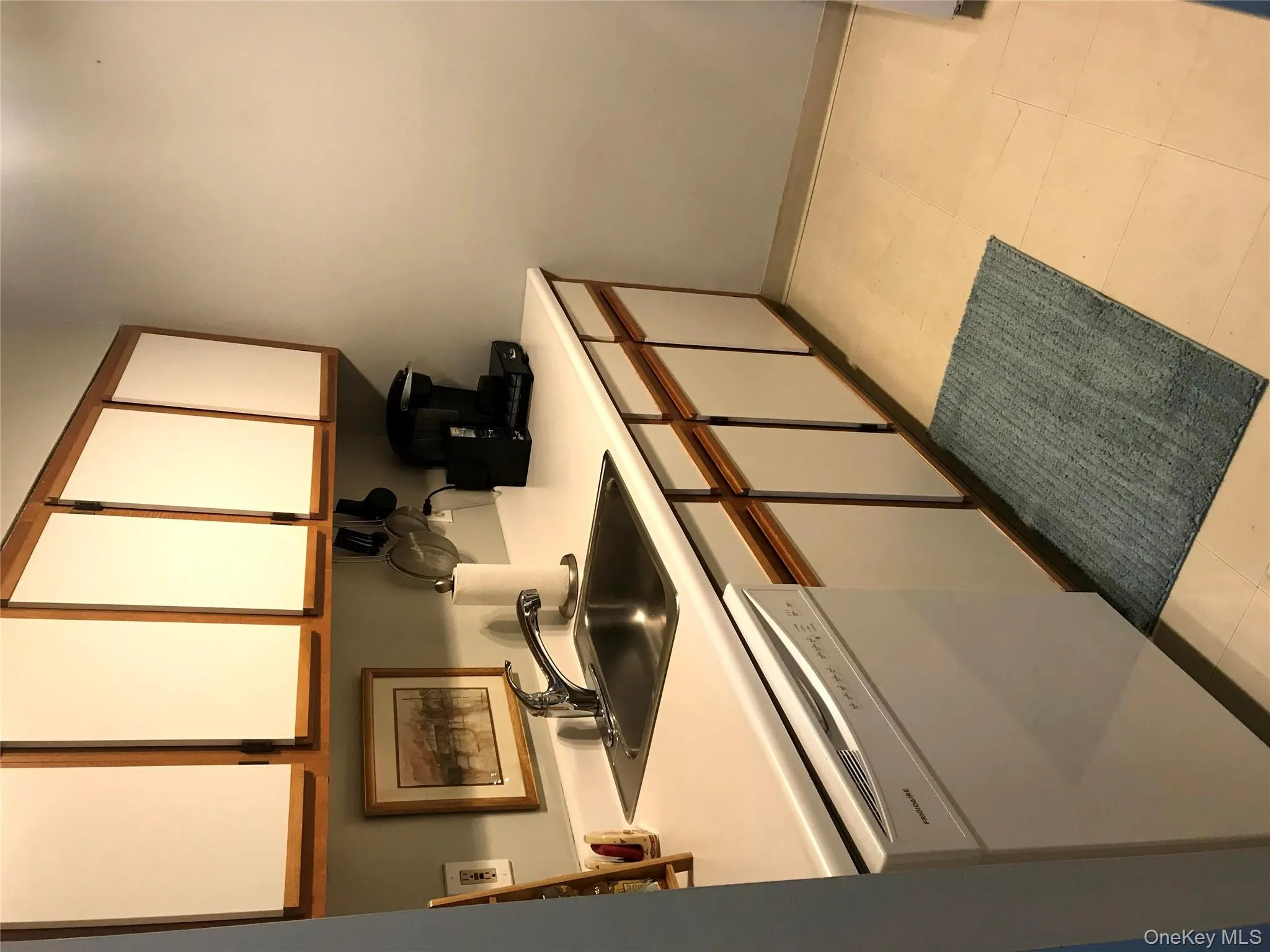 Kitchen featuring light countertops, white cabinets, dishwasher, and brown cabinetry Kitchen featuring light countertops, white cabinets, dishwasher, and brown cabinetry