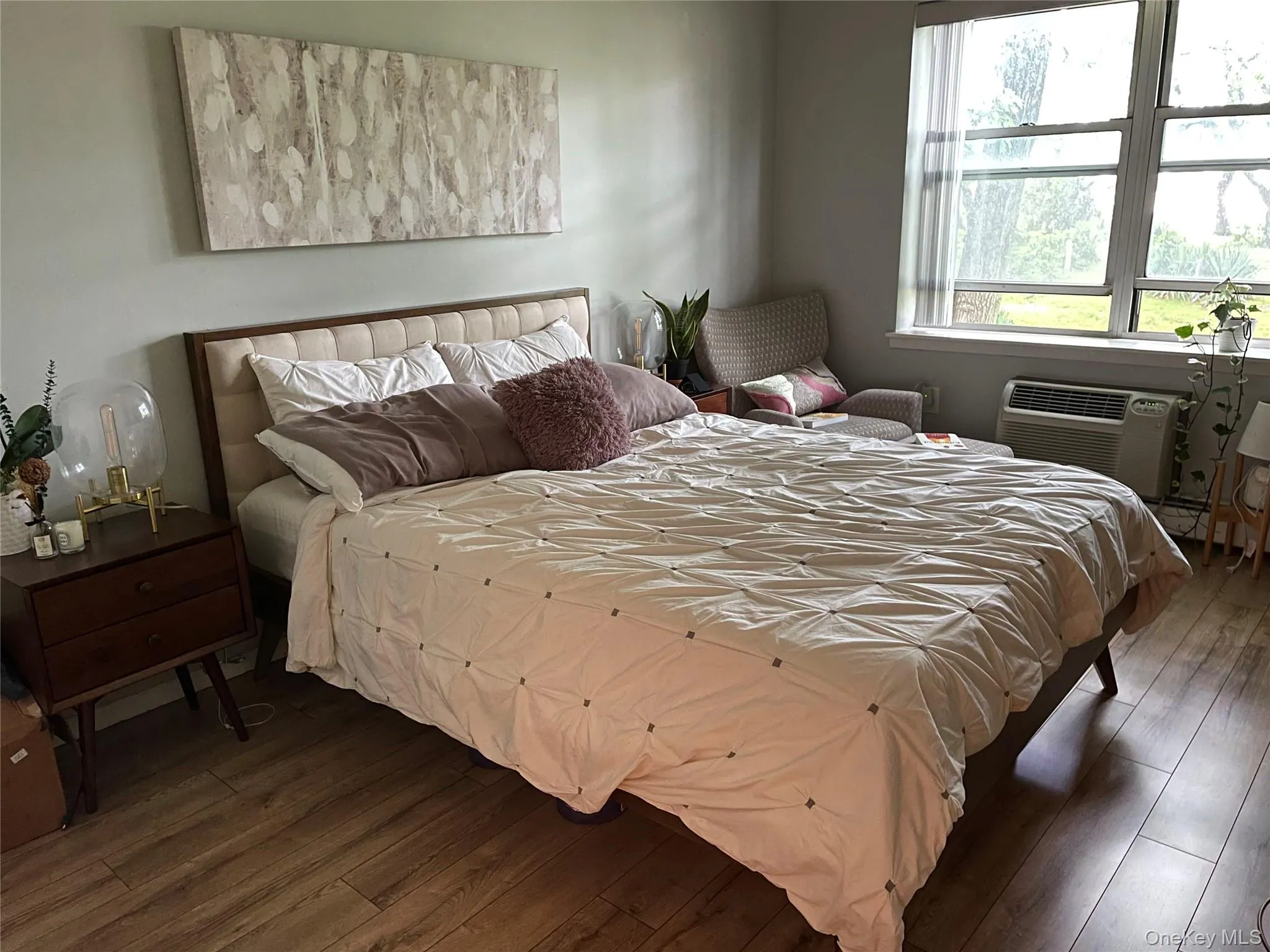 Bedroom with hardwood / wood-style flooring and an AC wall unit Bedroom with hardwood / wood-style flooring and an AC wall unit