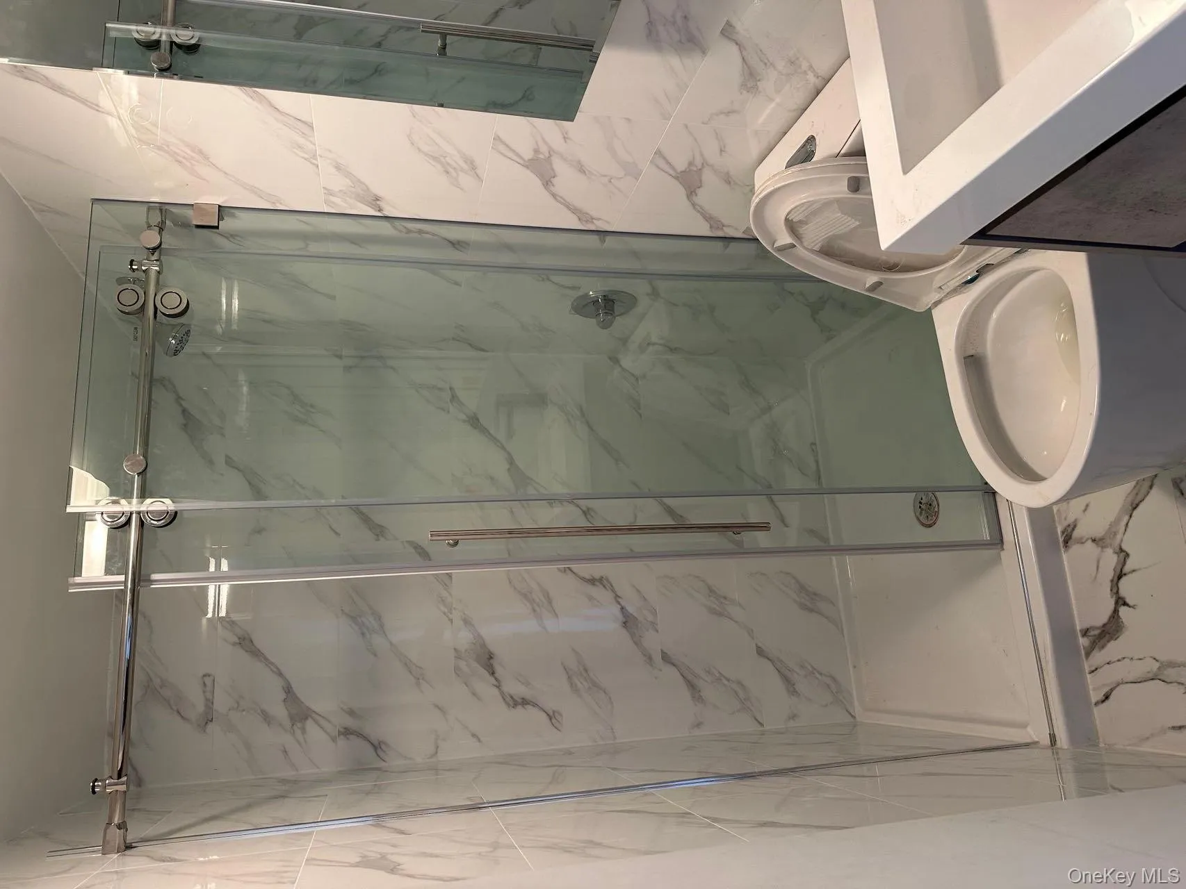 Bathroom featuring marble finish floors, tile walls, vanity, and a marble finish shower Bathroom featuring marble finish floors, tile walls, vanity, and a marble finish shower