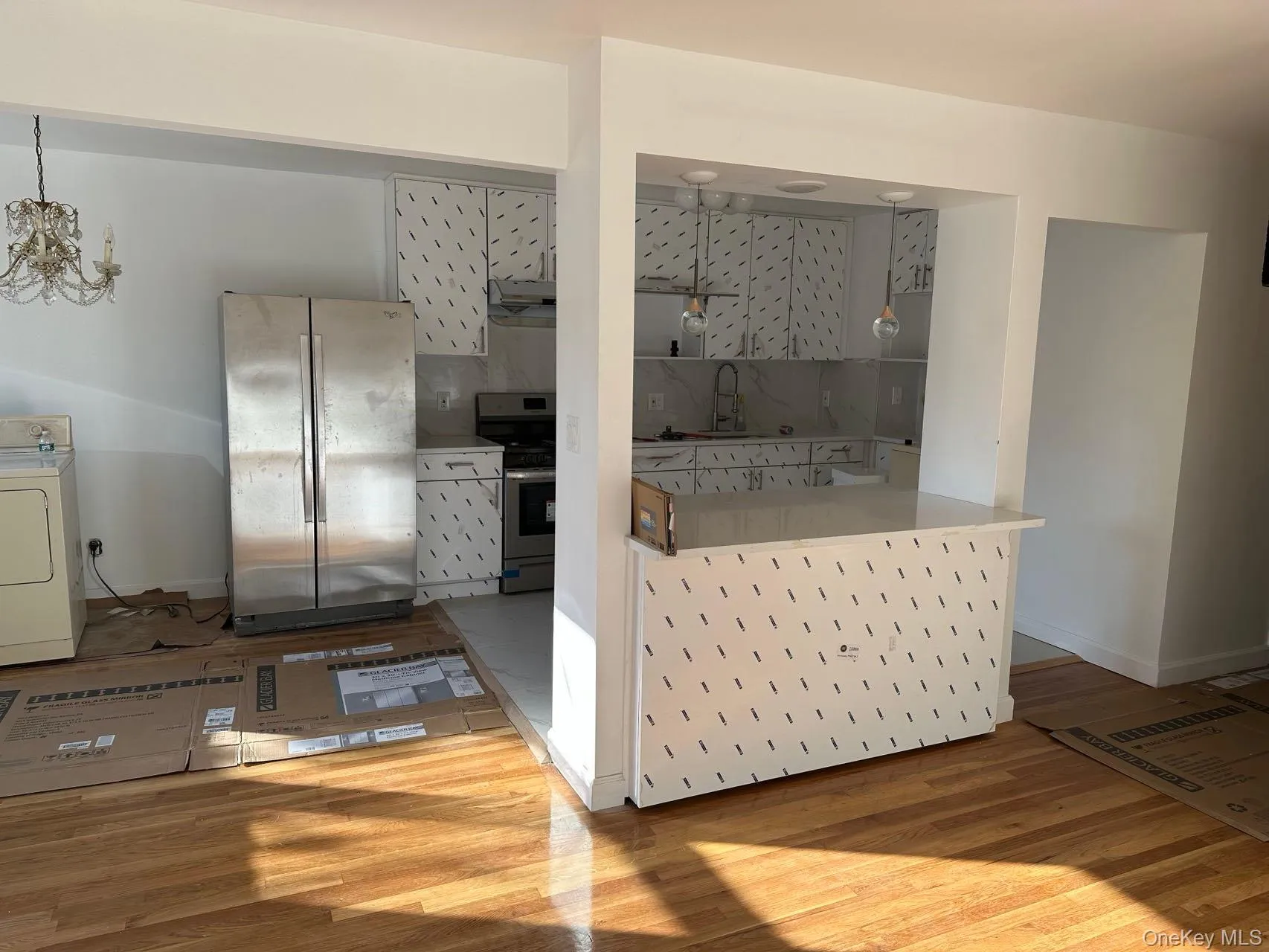 Kitchen featuring decorative backsplash, stainless steel appliances, washer / dryer, and light wood-style floors Kitchen featuring decorative backsplash, stainless steel appliances, washer / dryer, and light wood-style floors