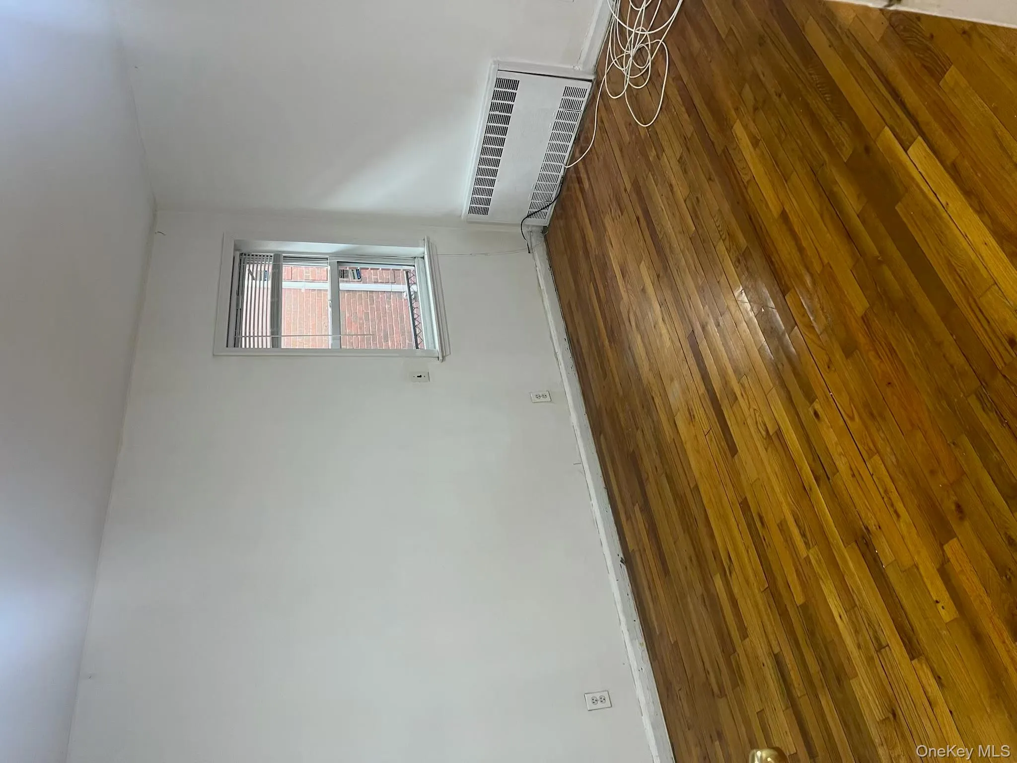 Spare room with dark wood-style flooring and radiator Spare room with dark wood-style flooring and radiator