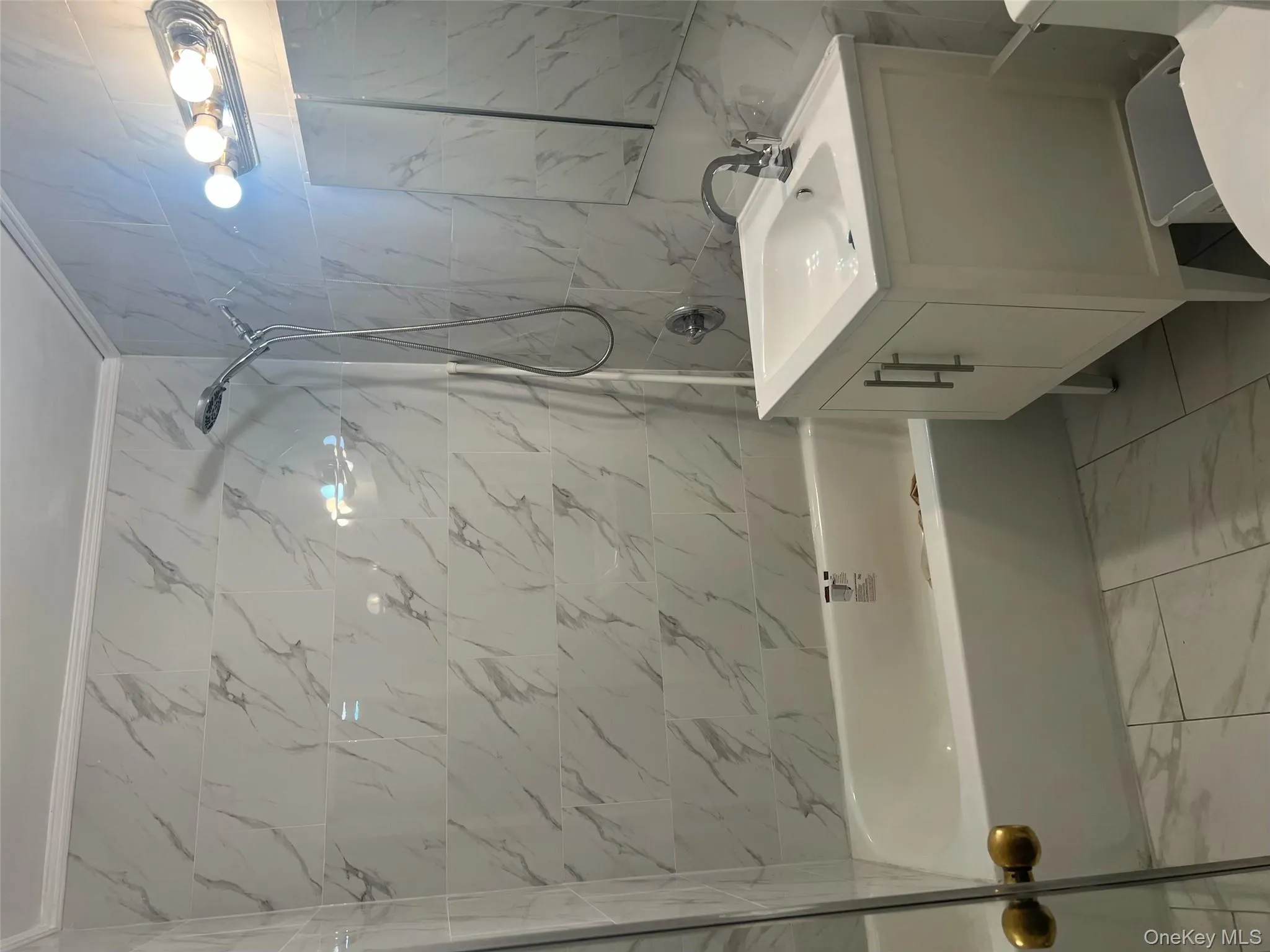 Full bath featuring light marble finish floors, tile walls, shower / bathtub combination, vanity, and crown molding Full bath featuring light marble finish floors, tile walls, shower / bathtub combination, vanity, and crown molding