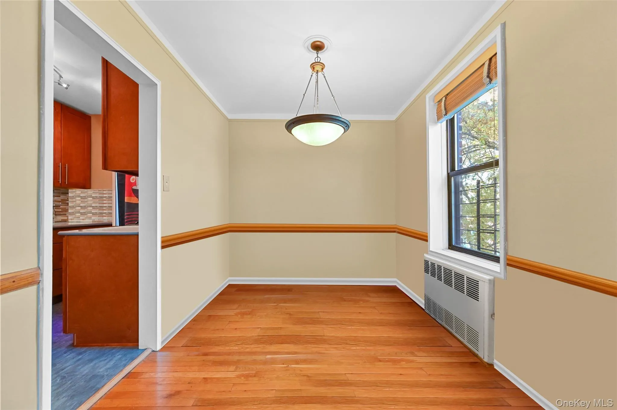Unfurnished dining area with radiator heating unit, light wood-style floors, and ornamental molding Unfurnished dining area with radiator heating unit, light wood-style floors, and ornamental molding